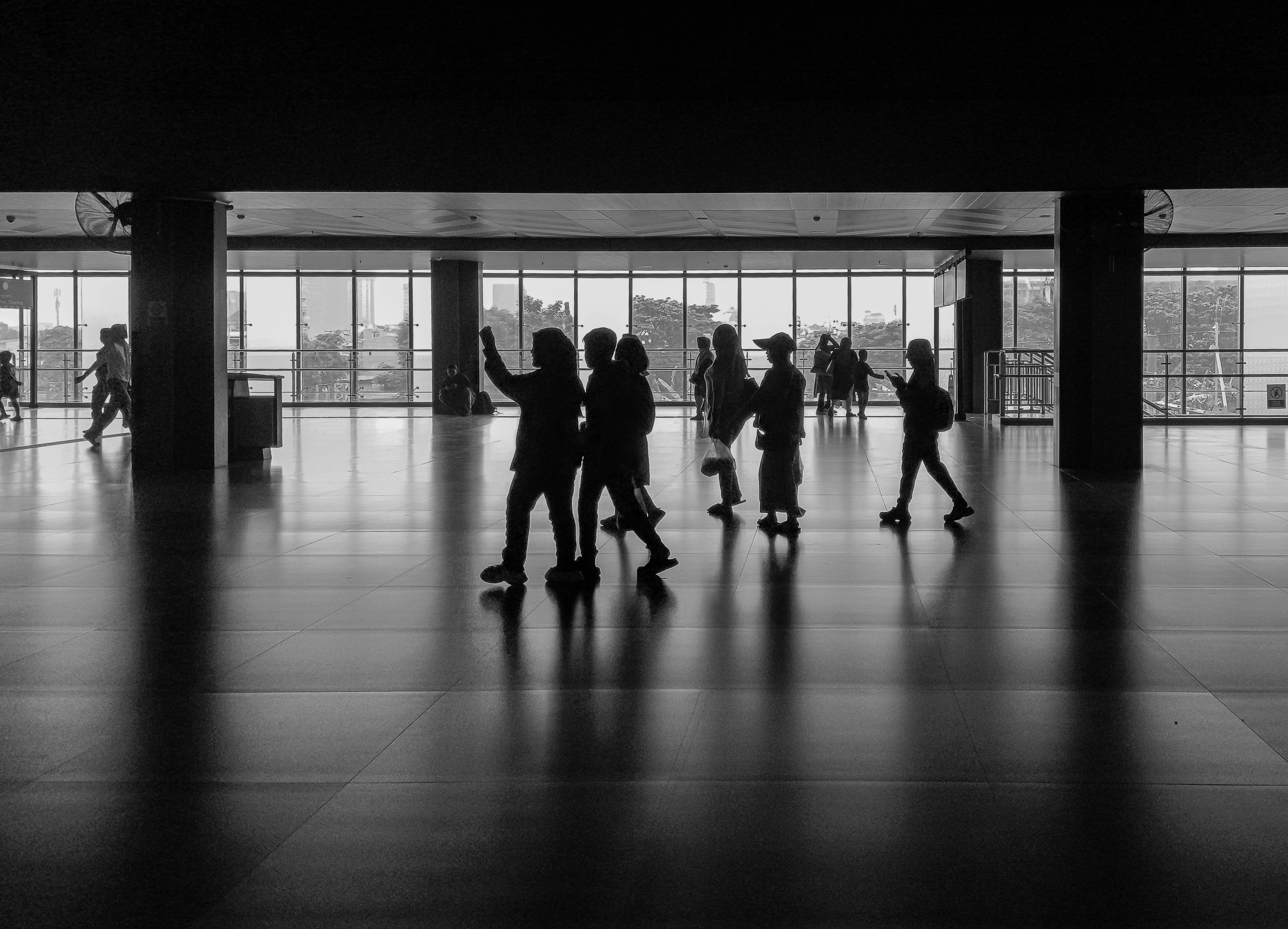 Free Silhouettes of people walking in an indoor Jakarta station, shot in black and white. Stock Photo