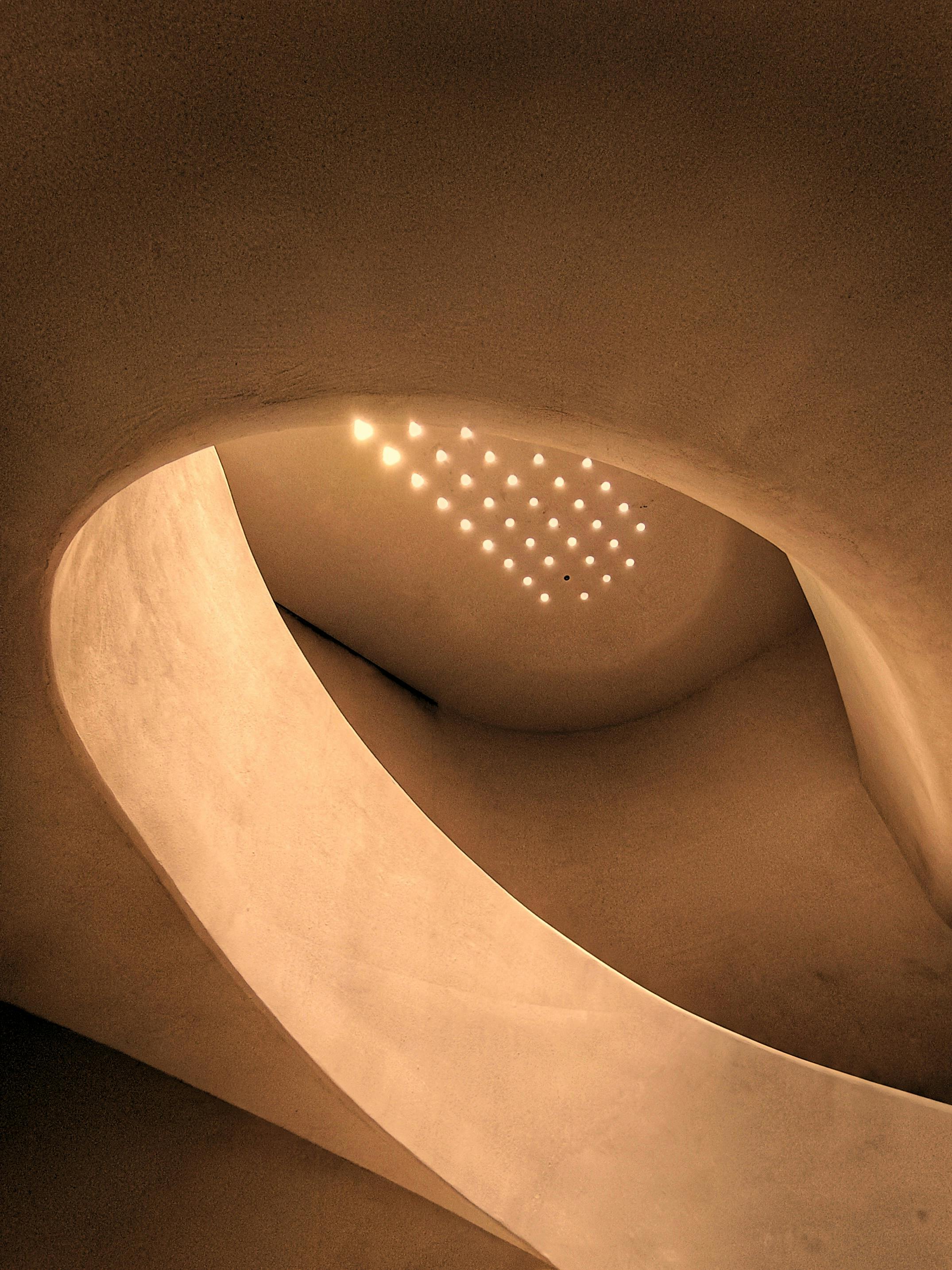 Gratis Un'affascinante scala a chiocciola dal design architettonico artistico e dall'illuminazione calda. Foto a disposizione