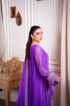 Woman in elegant embroidered dress posing indoors, showcasing Eastern fashion style in Lahore.