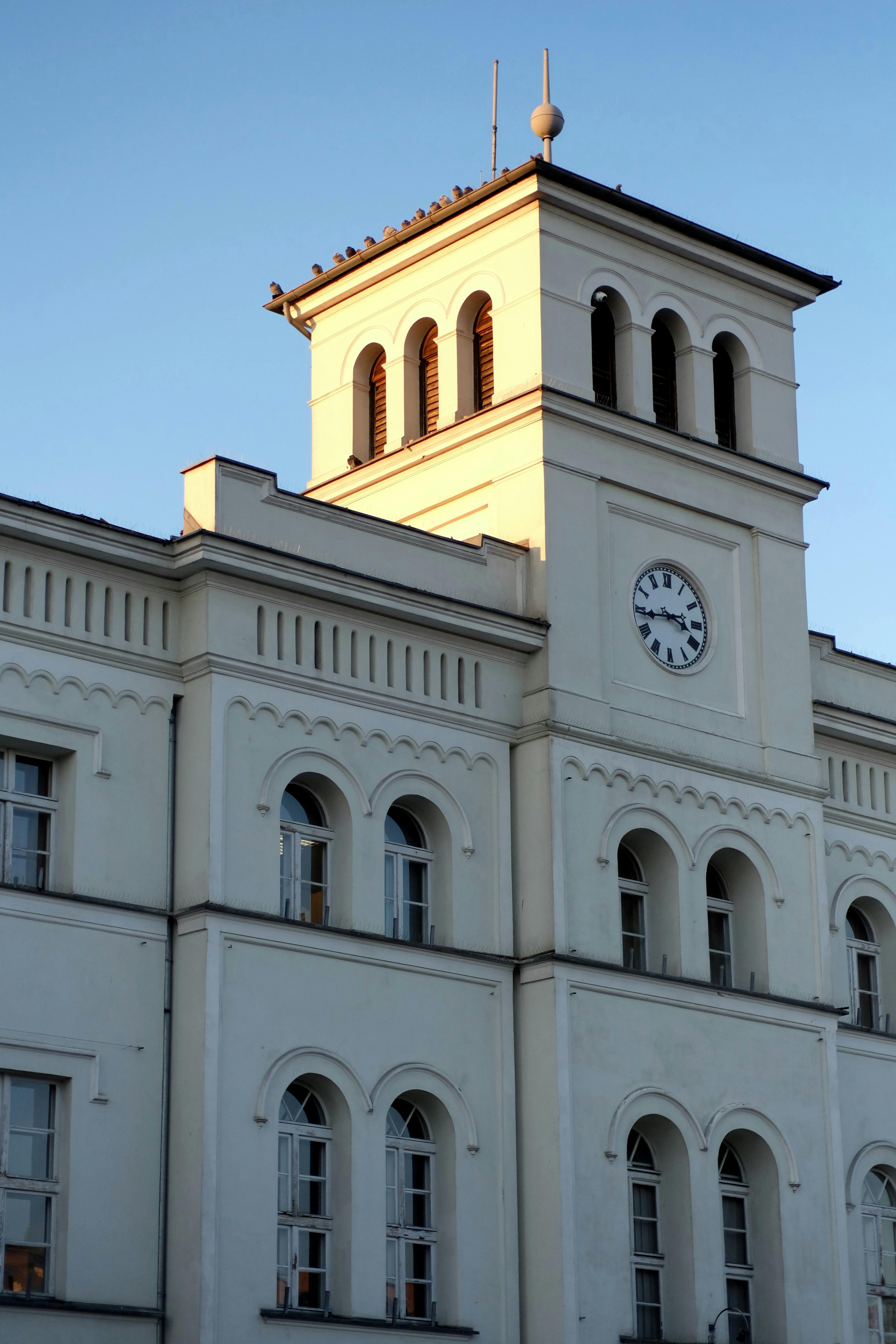 Ücretsiz Gün batımı ışığıyla aydınlanan saat kulesiyle zarif mimarisini sergileyen klasik bir tarihi bina. Stok Fotoğraflar