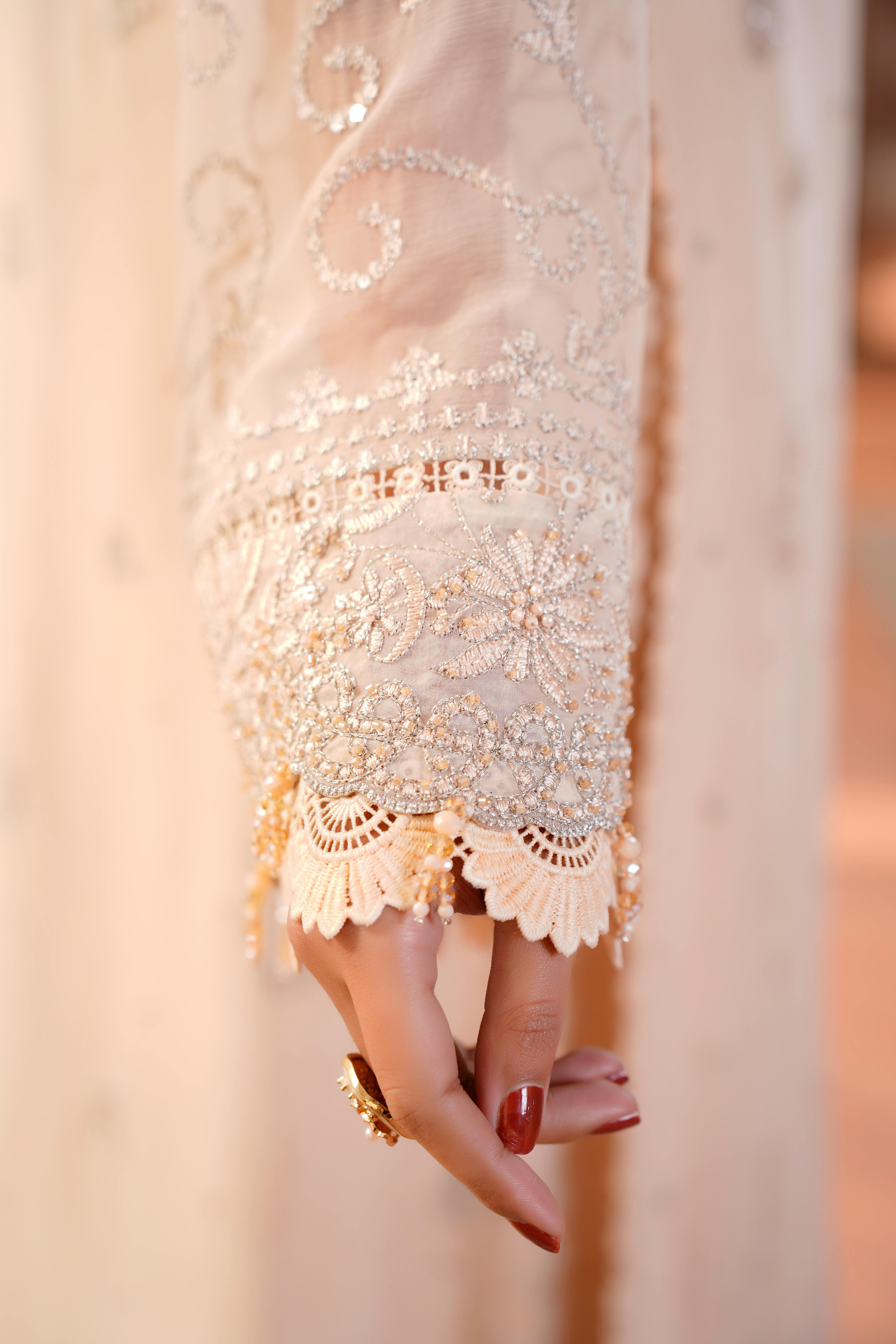 Free Close-up image of an intricately embroidered dress sleeve in soft lighting, showcasing elegant fashion details. Stock Photo