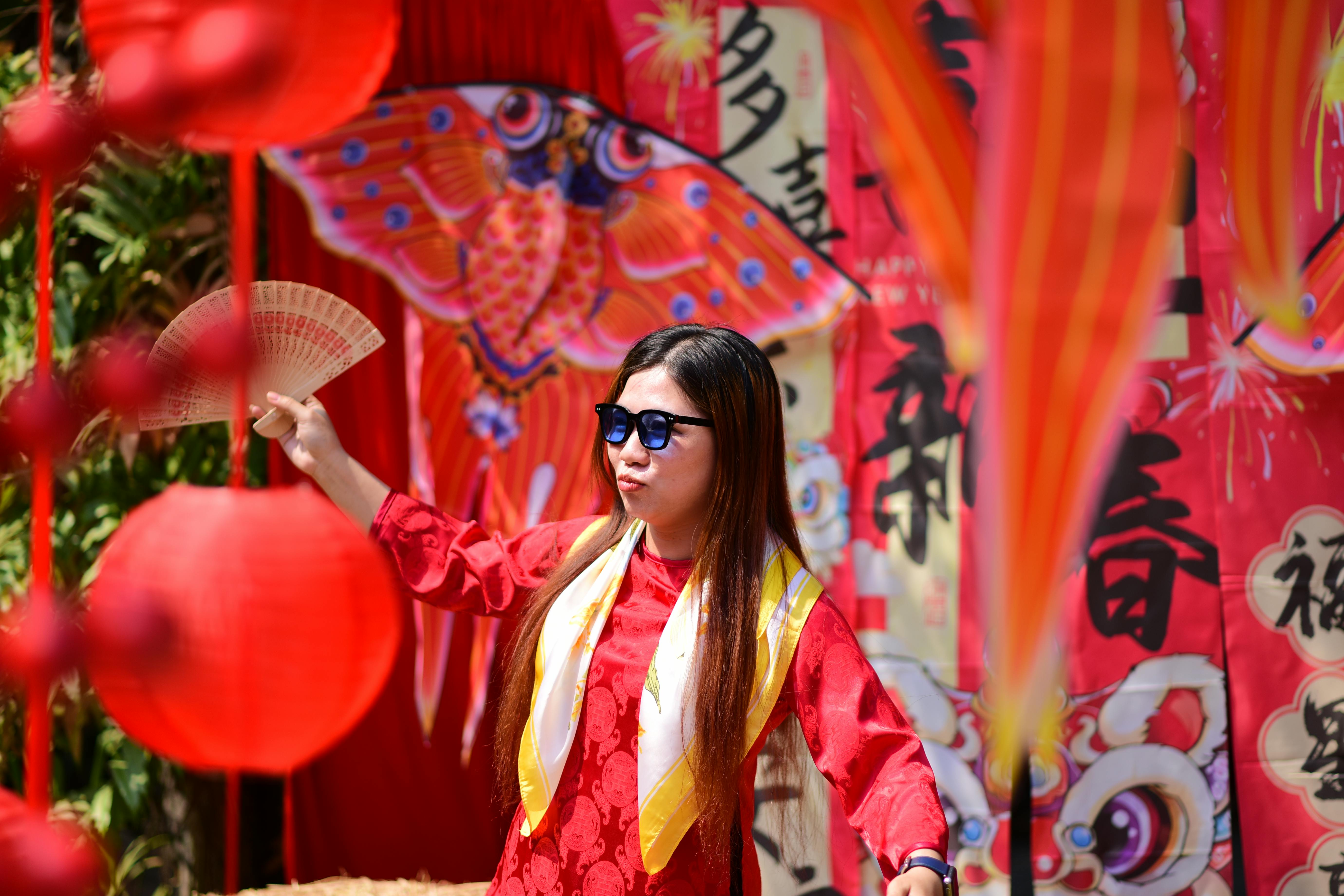 gratis Vrouw in rode jurk geniet van een levendig festival met lantaarns en culturele versieringen. Stockfoto