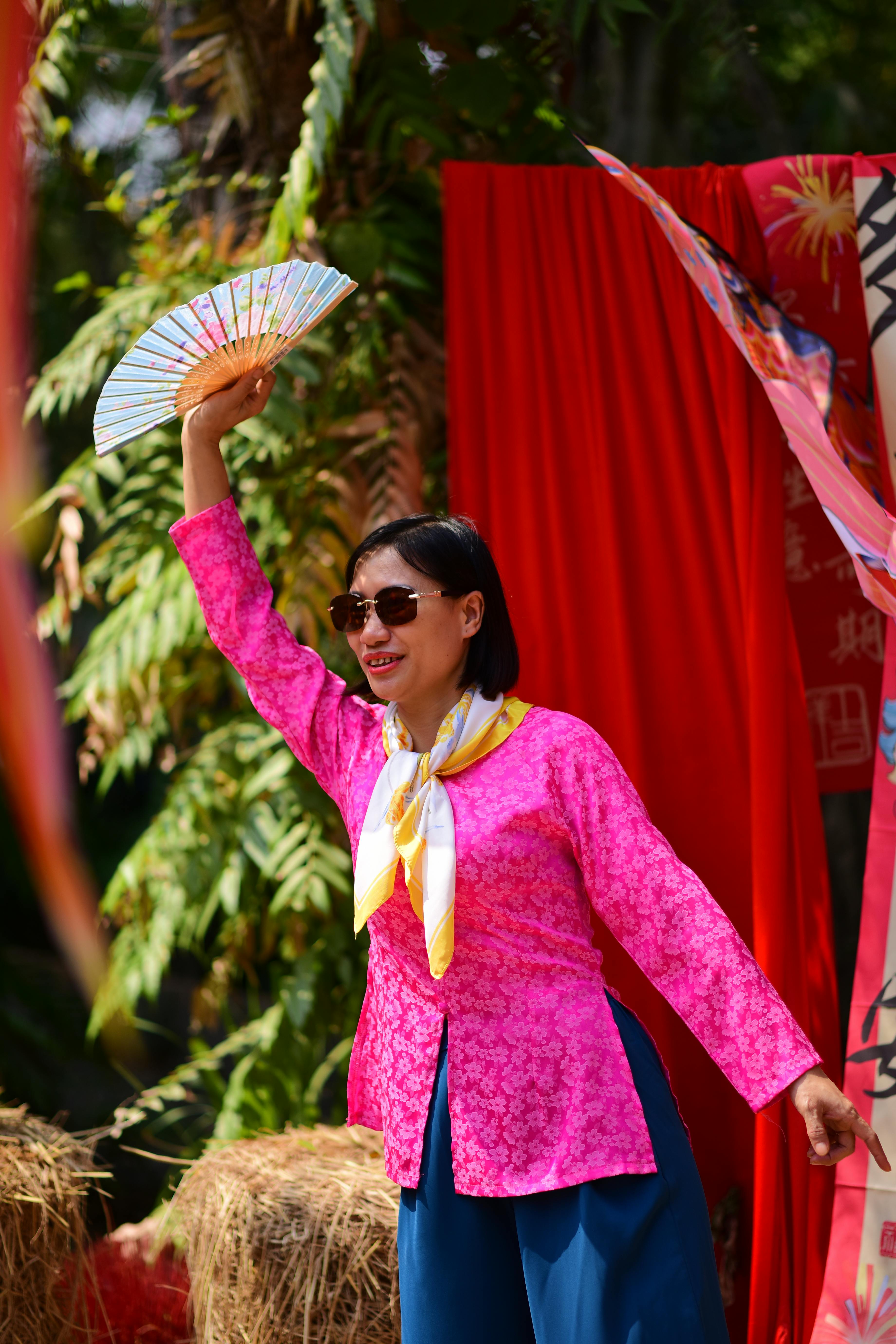 Gratis Seorang wanita mengenakan pakaian berwarna cerah sedang menampilkan tarian tradisional di luar ruangan. Foto Stok