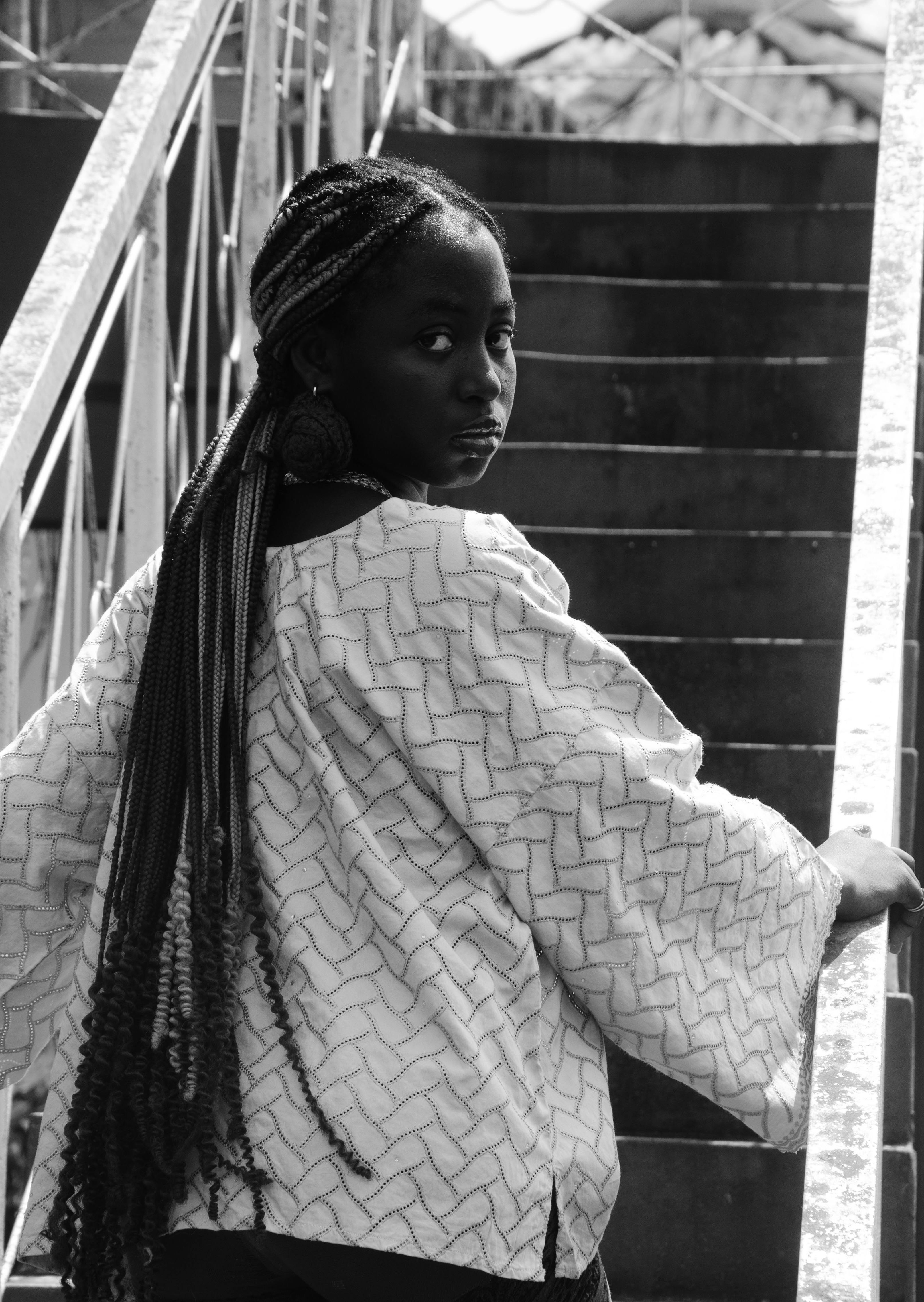 Miễn phí Bức chân dung đen trắng ấn tượng của một người phụ nữ với mái tóc dài tết bím trên cầu thang. Ảnh lưu trữ