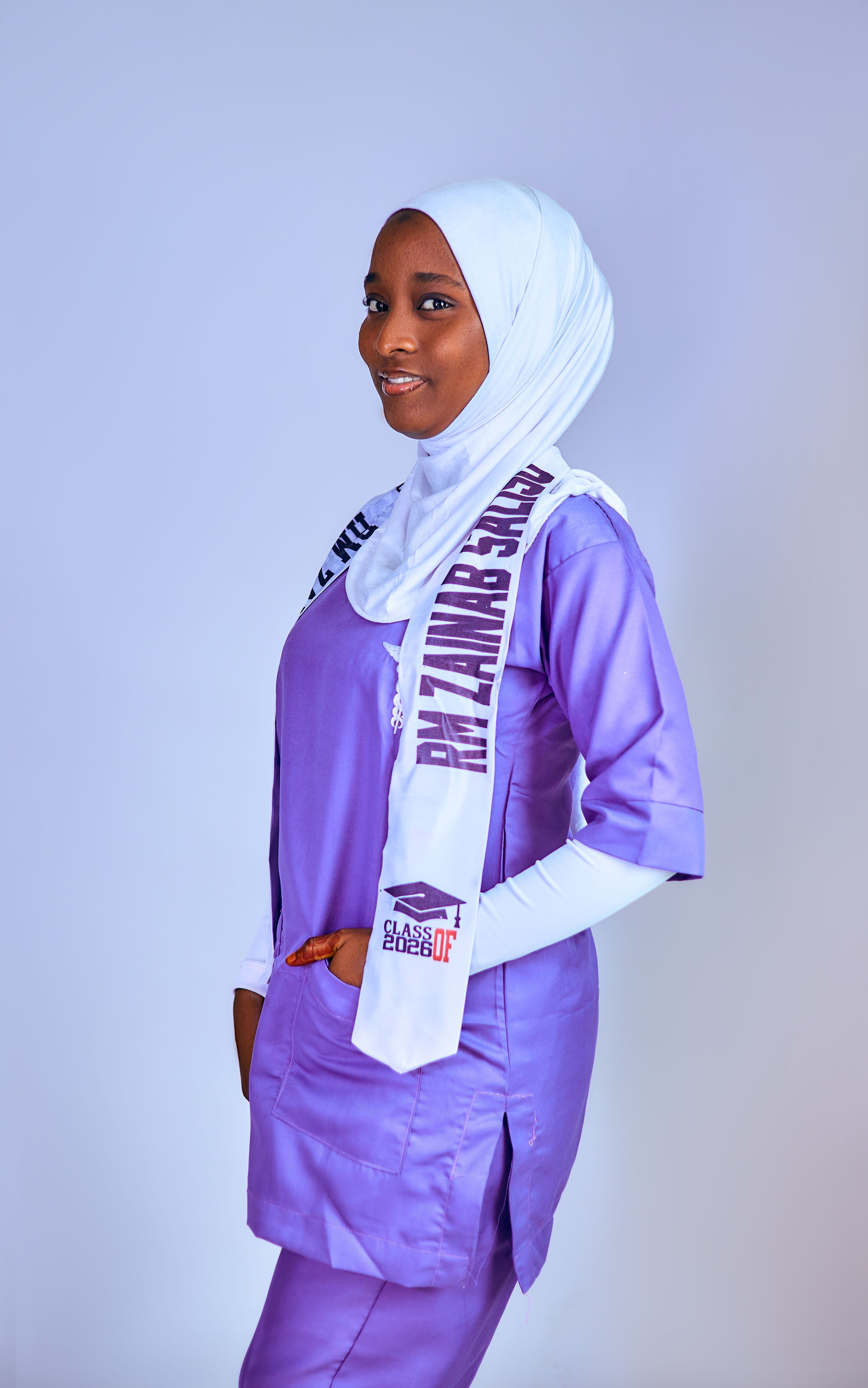 Young woman in graduation attire smiling against a plain background.