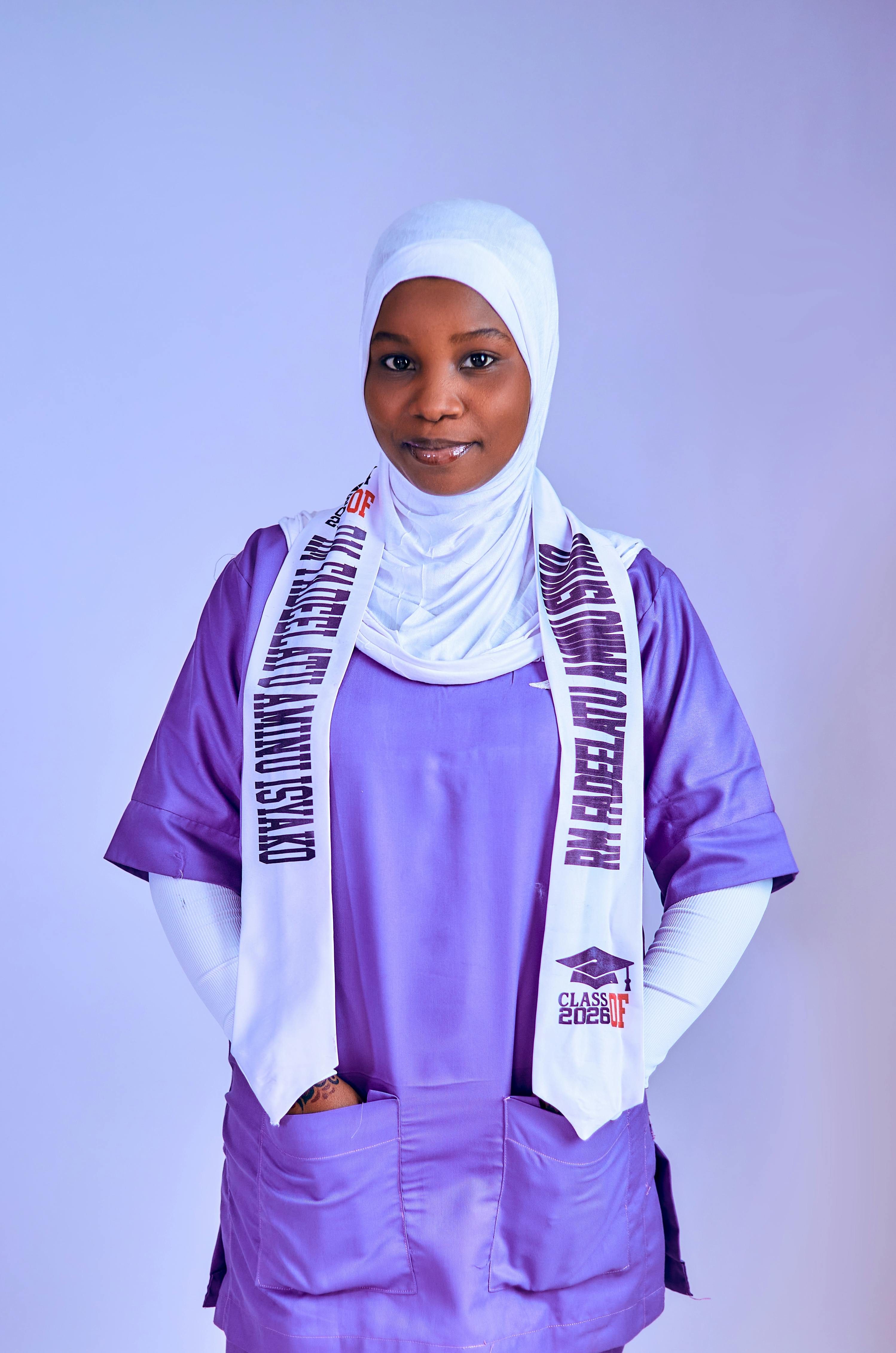 Confident young woman in a purple graduation outfit and hijab, celebrating academic success.