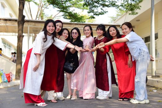A group of smiling women in traditional Vietnamese dresses gathers outdoors expressing friendship and togetherness.