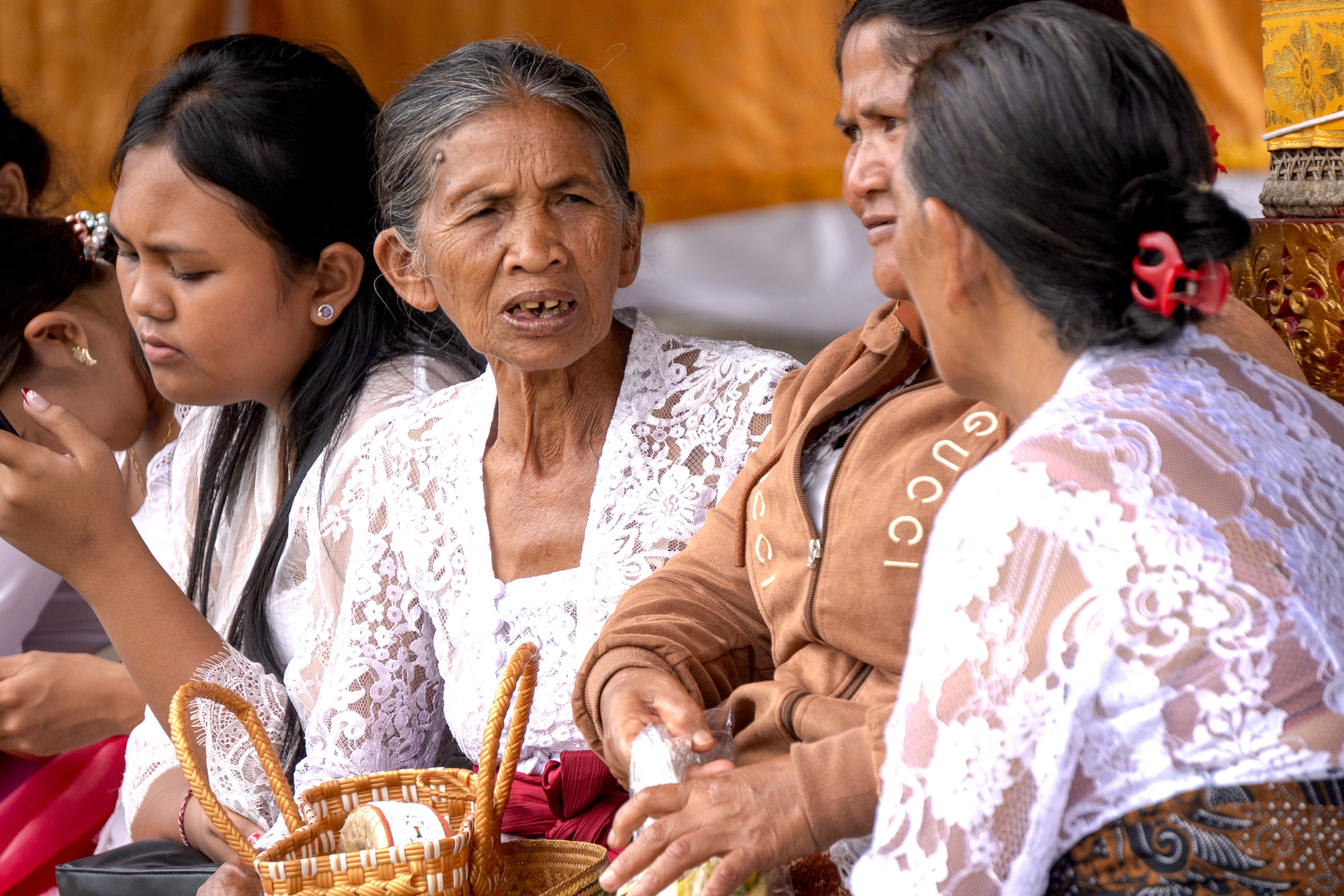 Balinese women engage in conversation during a traditional ceremony.