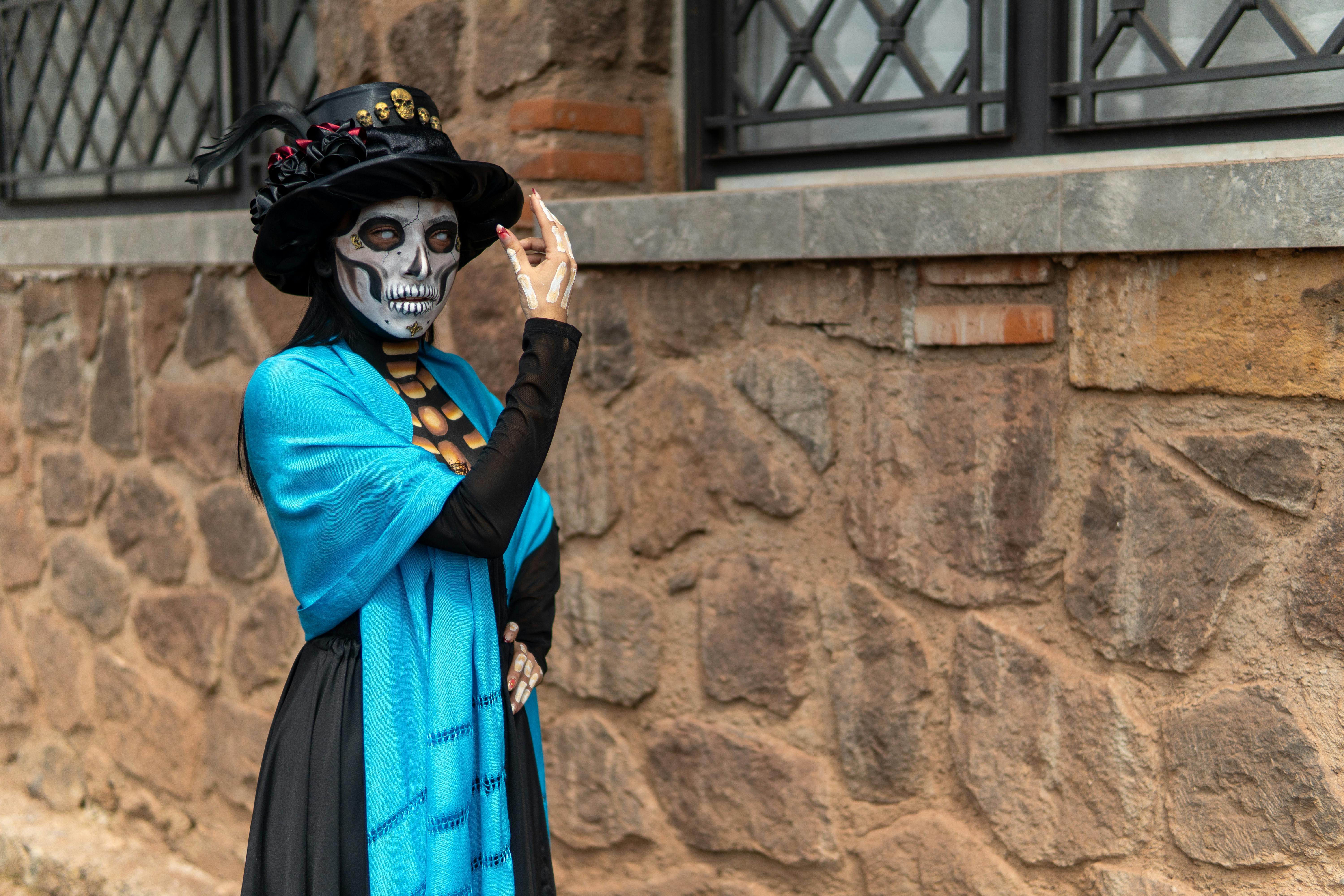 Gratis Seorang wanita berdandan sebagai Catrina dengan pakaian berwarna cerah, merayakan tradisi Meksiko di luar ruangan. Foto Stok