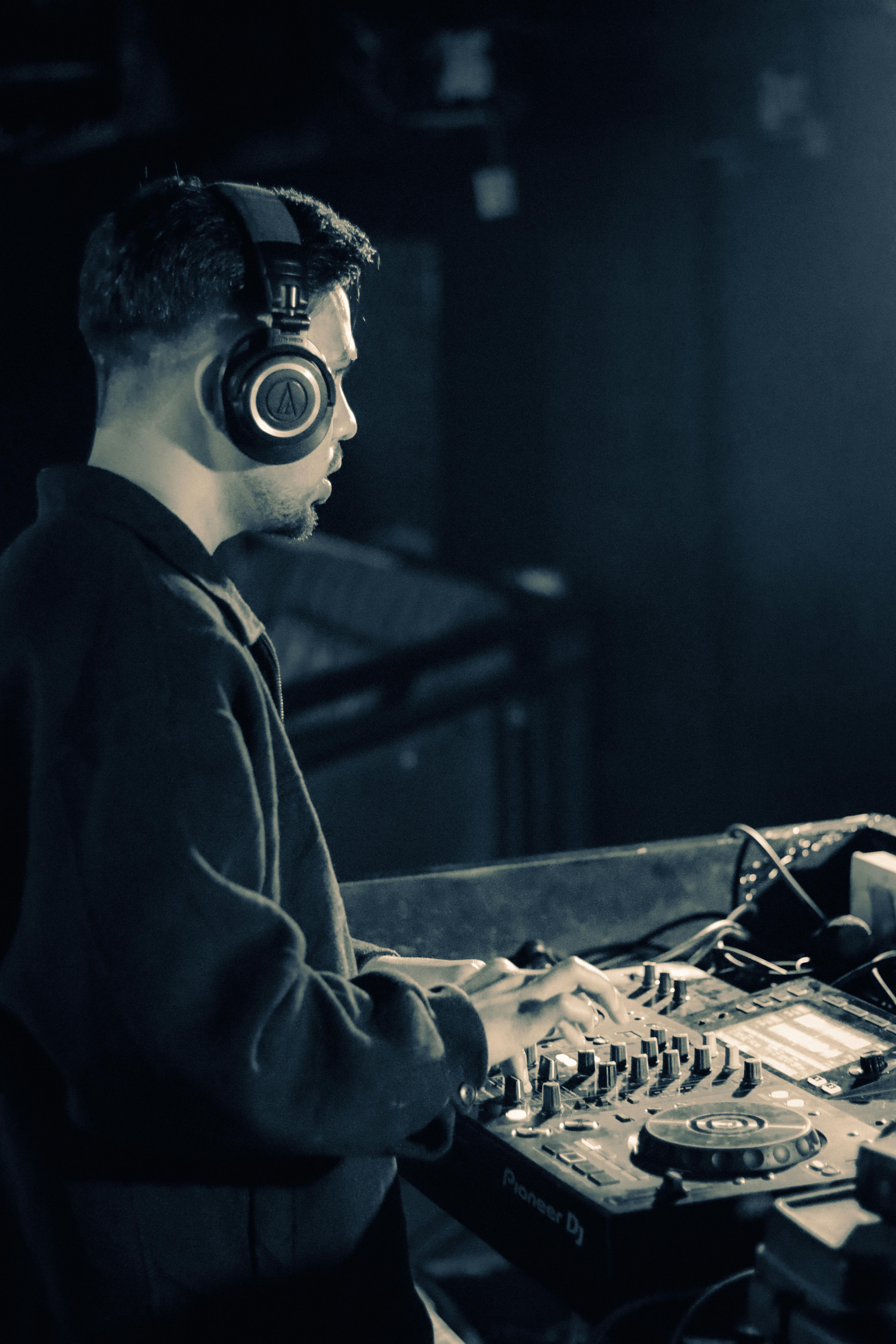 Miễn phí Hình ảnh đầy cuốn hút về một DJ đang biểu diễn trực tiếp, phối nhạc bằng thiết bị chuyên nghiệp trong một không gian hộp đêm sôi động. Ảnh lưu trữ