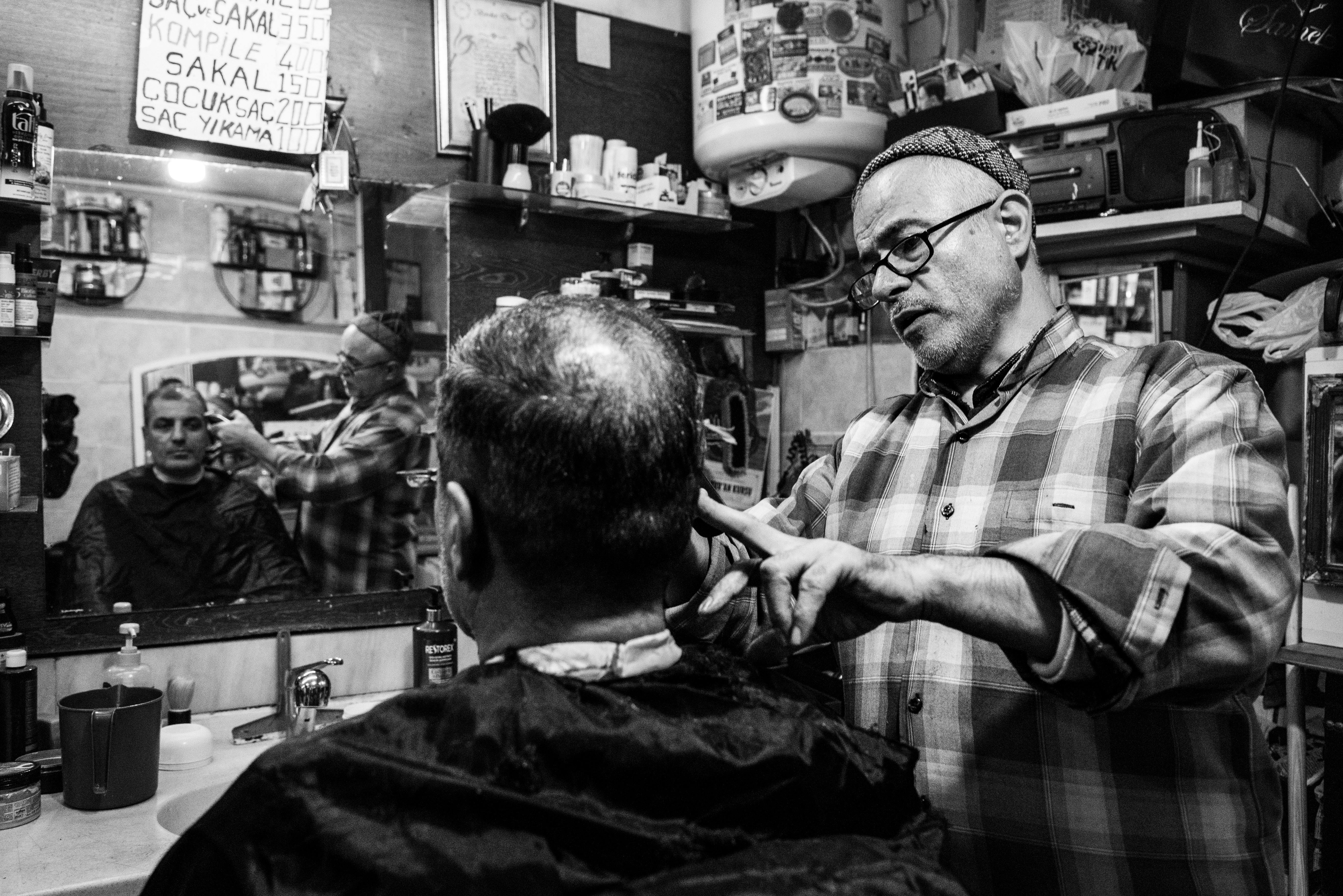 Безкоштовне Перукар майстерно стриже волосся клієнту в стамбульській перукарні. стокове фото