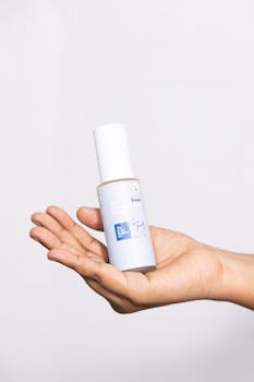 A hand holding a skincare serum bottle, ideal for beauty and skincare promotions.
