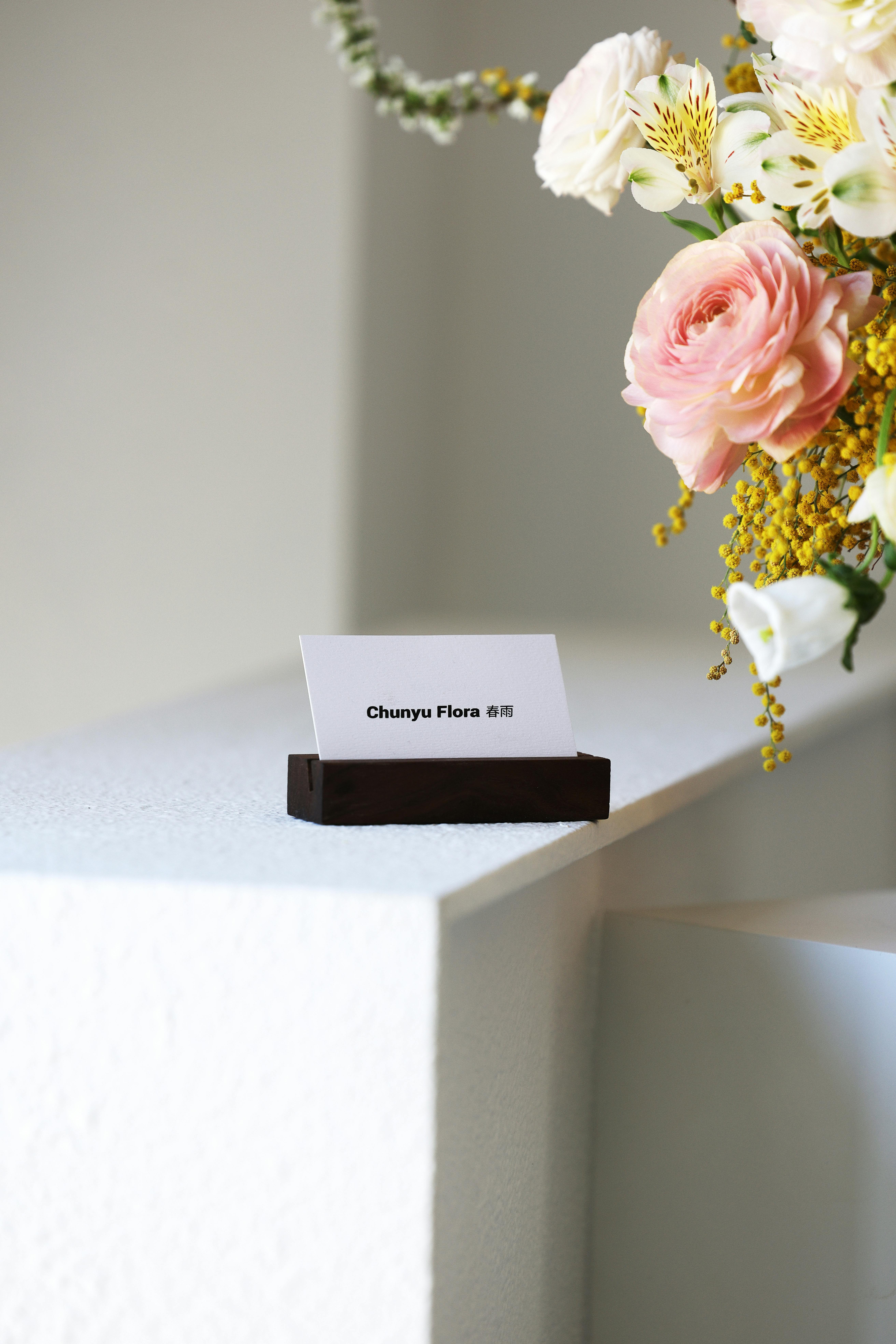 Free Chic floral bouquet next to a business card on a minimalist surface. Stock Photo