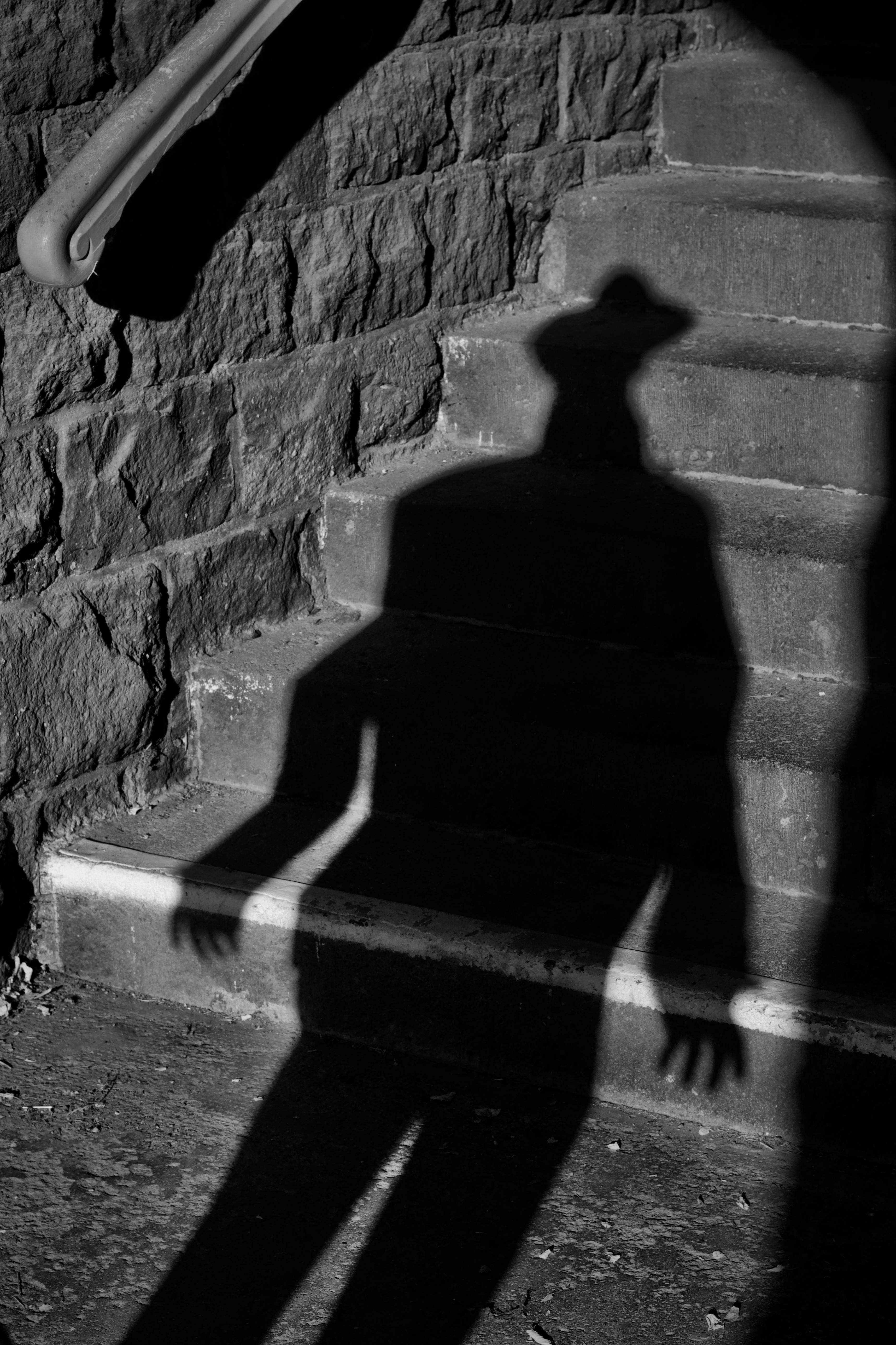 gratis De schaduw van een persoon met een hoed op de stenen trappen creëert een mysterieuze sfeer. Stockfoto