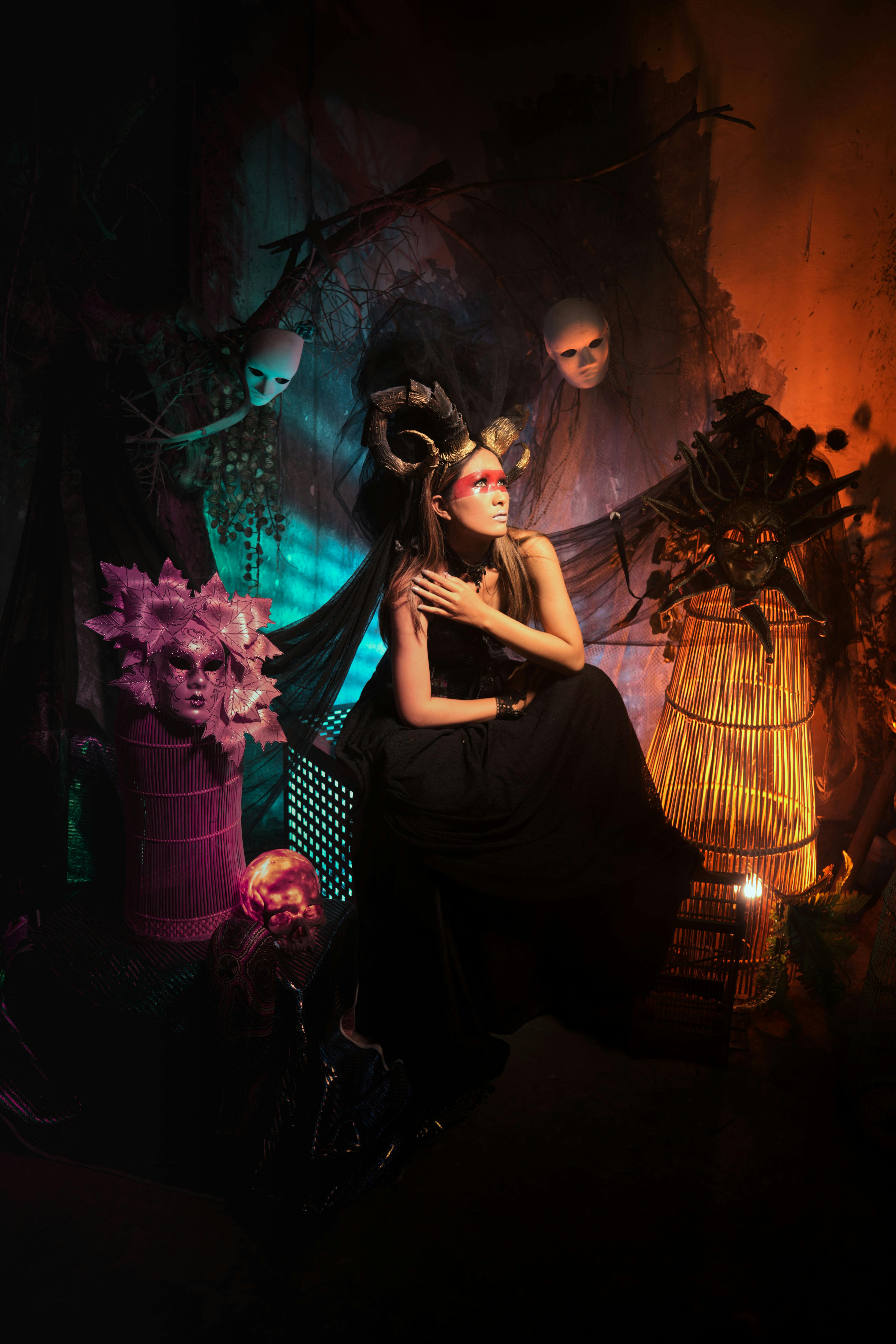 Gratuit Une femme dans un environnement mystique, avec des masques et un éclairage dramatique. Photos