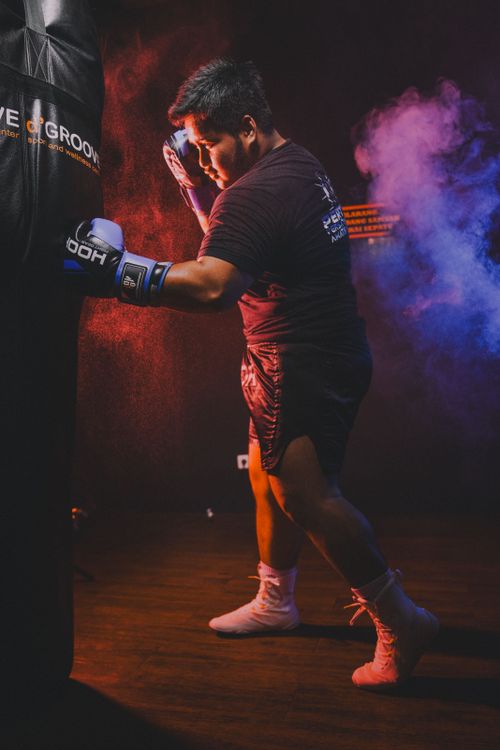 Free A boxer intensely trains with a punching bag in a dimly lit gym. Stock Photo