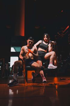 Athletic man and woman lifting weights in an indoor gym.