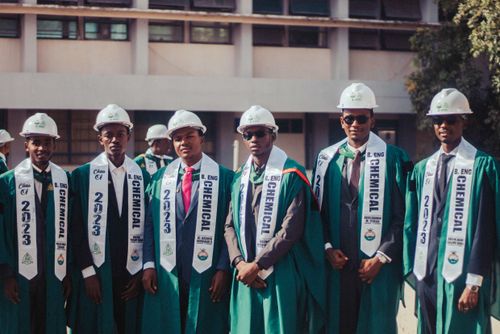 Free Group of chemical engineering graduates in hard hats and gowns celebrating their achievement. Stock Photo