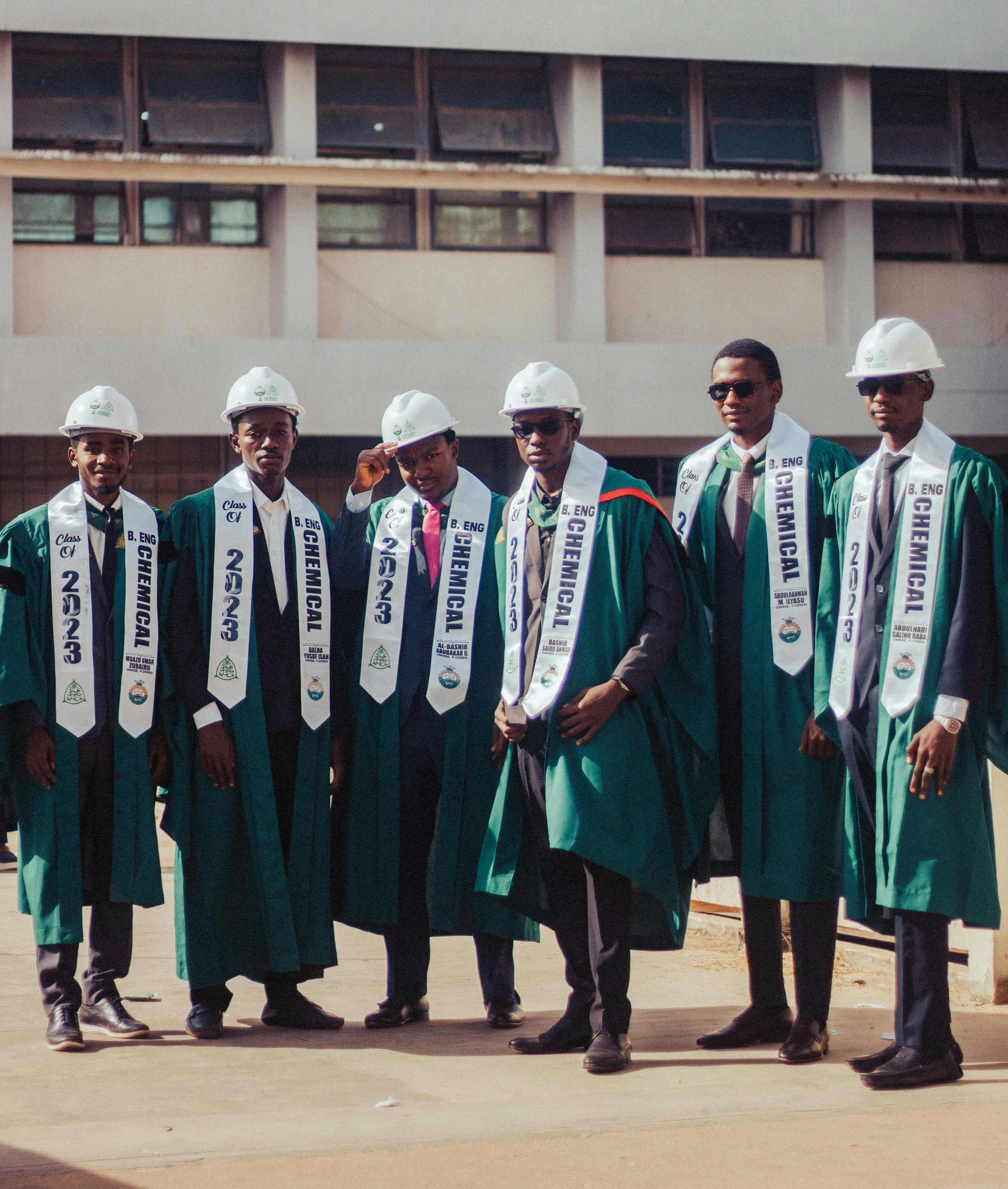 Group of chemical engineering graduates wearing caps and gowns, celebrating their graduation day outdoors.