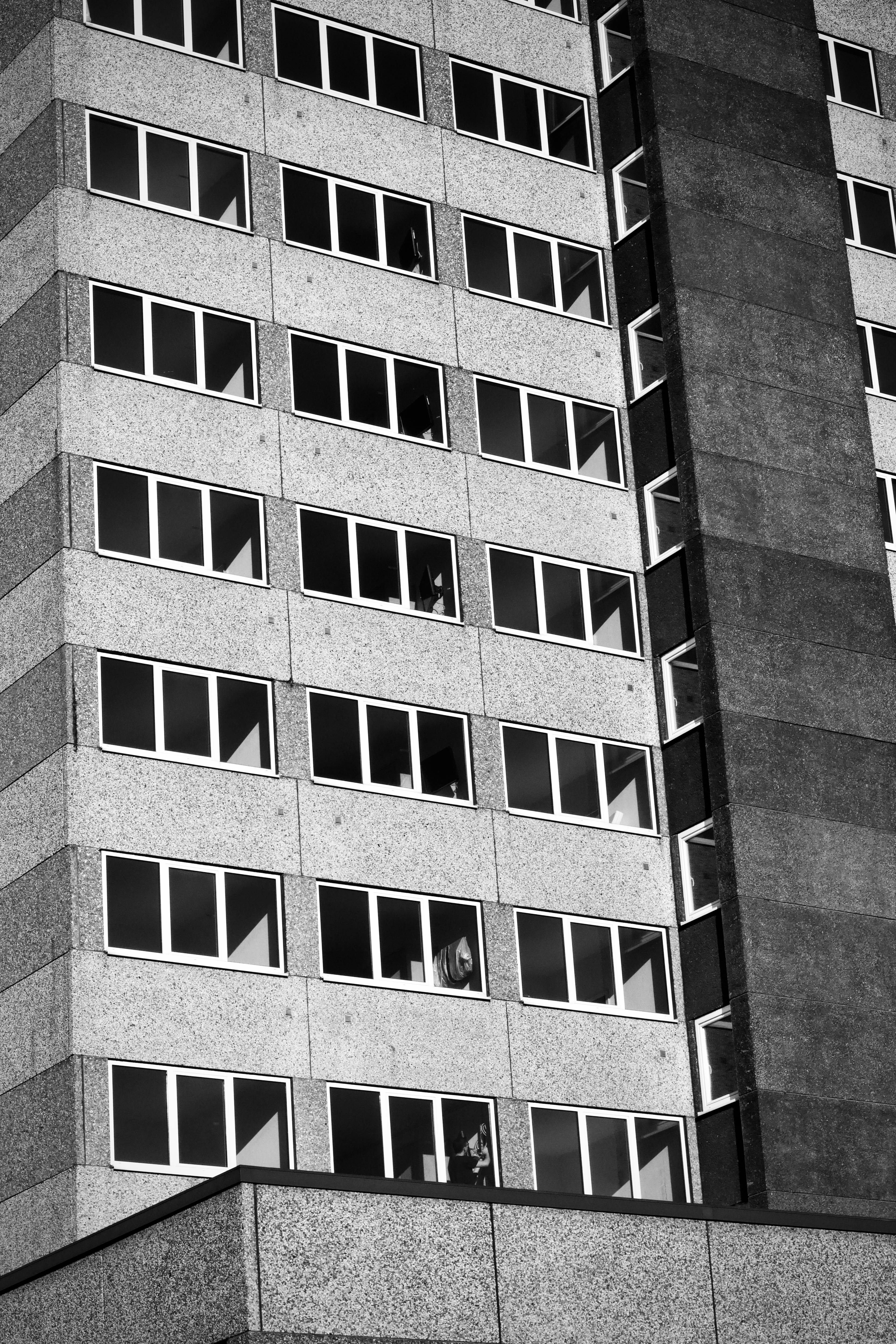 Ücretsiz Tekrarlayan pencerelere sahip geometrik bir yüksek bina cephesinin siyah beyaz fotoğrafı. Stok Fotoğraflar
