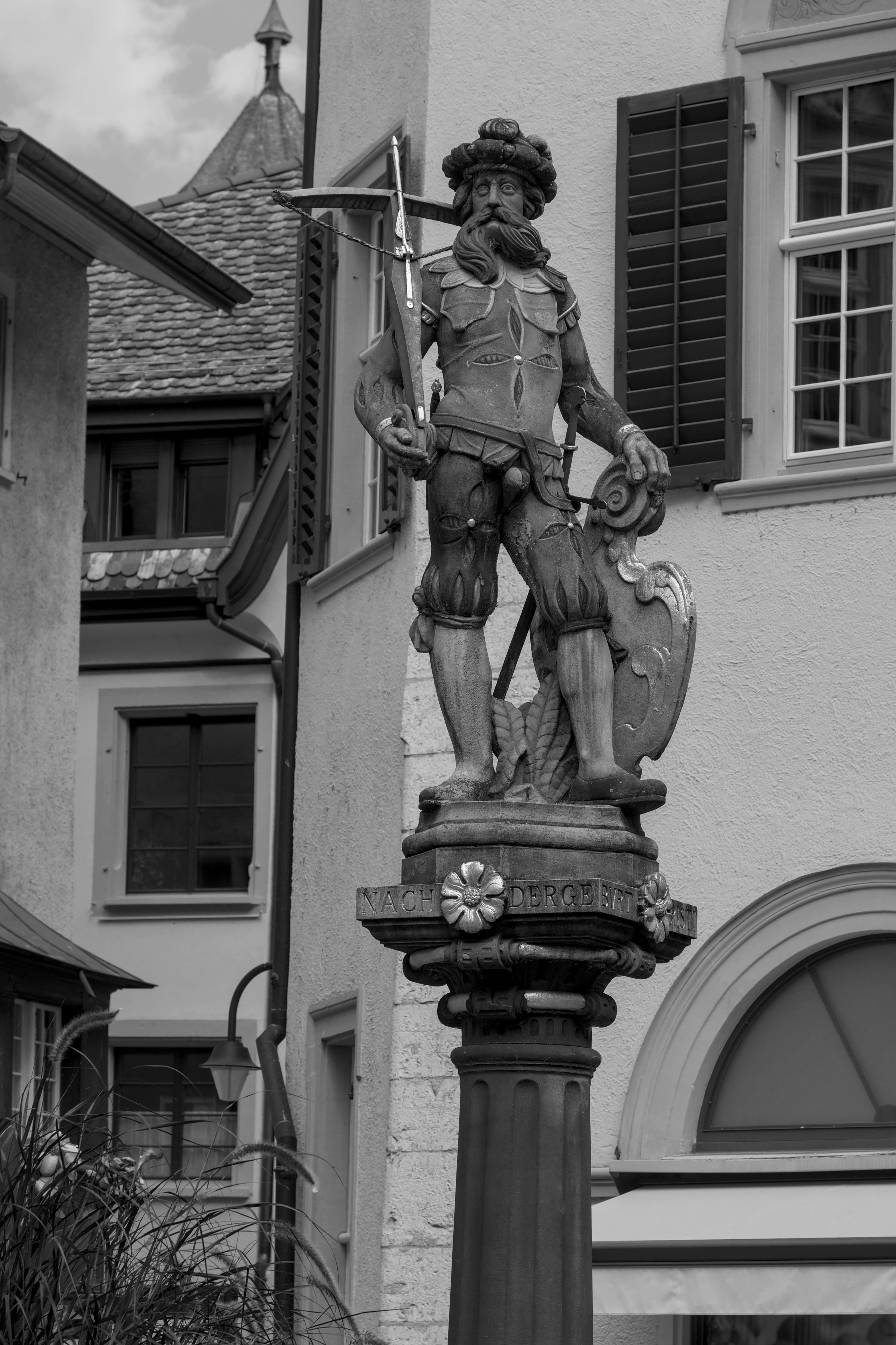 Gratis Fotografía en blanco y negro de una estatua europea en un entorno de pueblo encantador, resaltando los detalles arquitectónicos. Foto de stock
