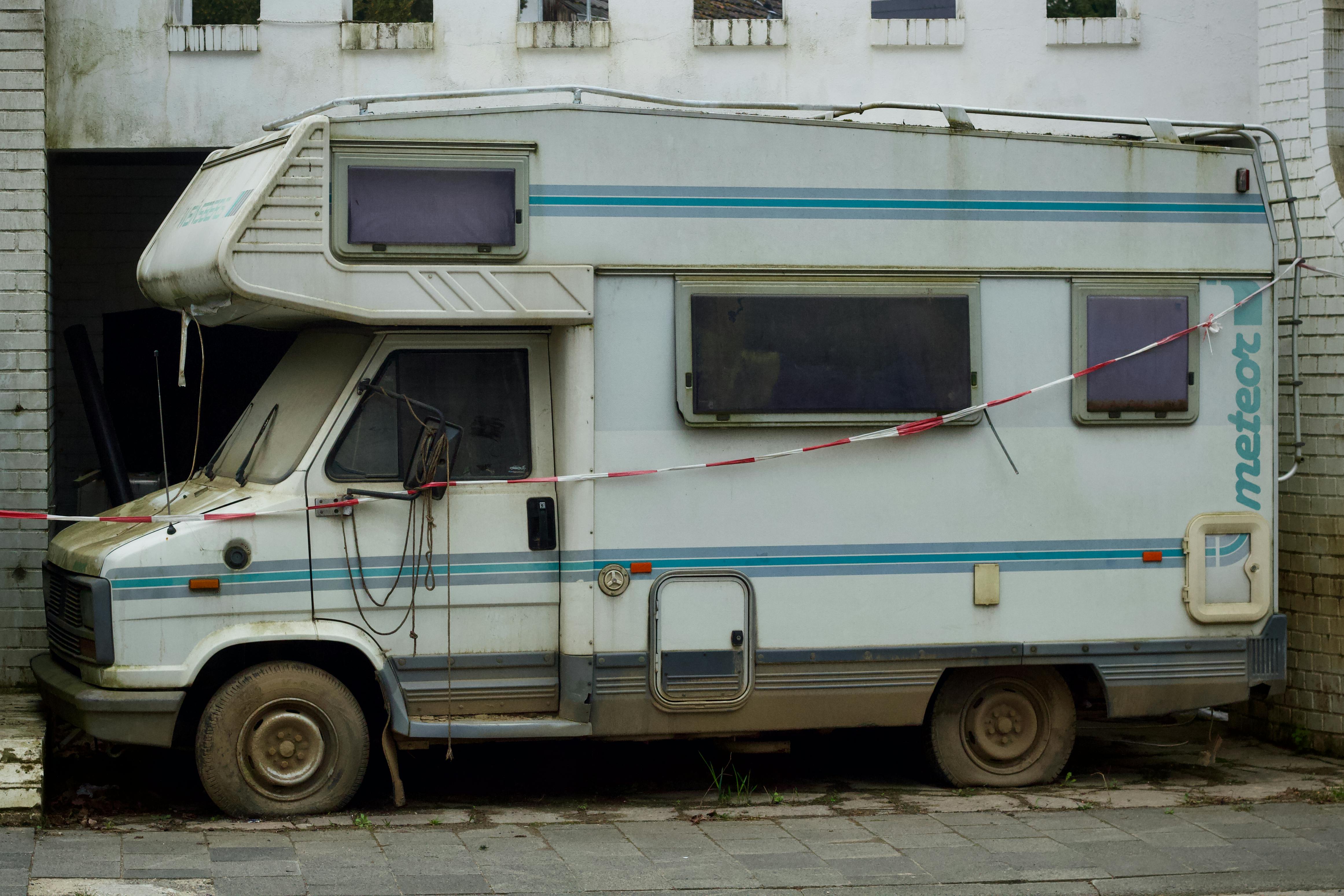 An old, abandoned camper van parked in an alleyway, showcasing urban decay.