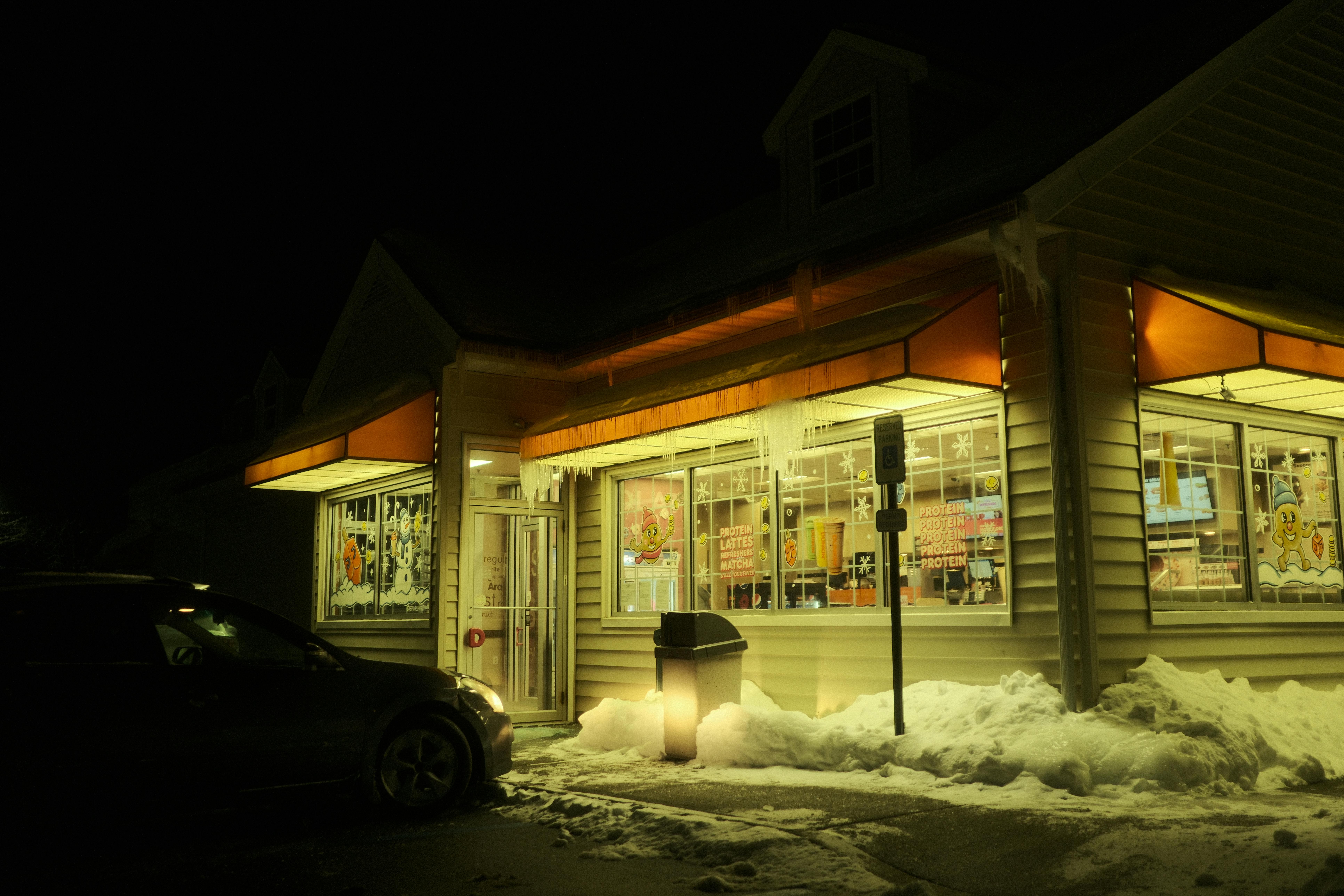 Kostnadsfria En närbutik på natten med snö och istappar som lyser upp gatan på vintern. Stock foto