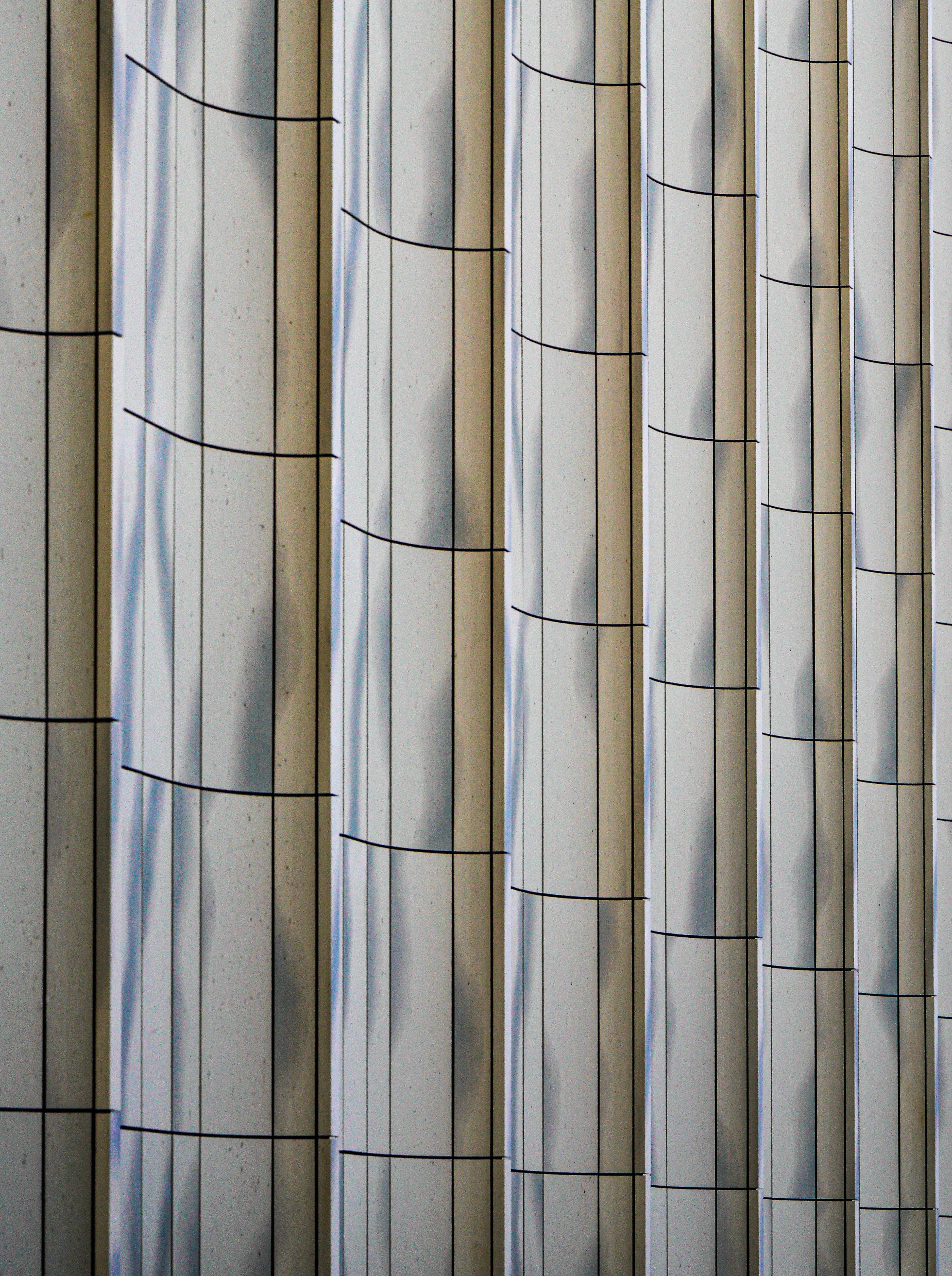 gratis Close-up van de gebogen, minimalistische gevel van een modern gebouw met een herhalend patroon. Stockfoto