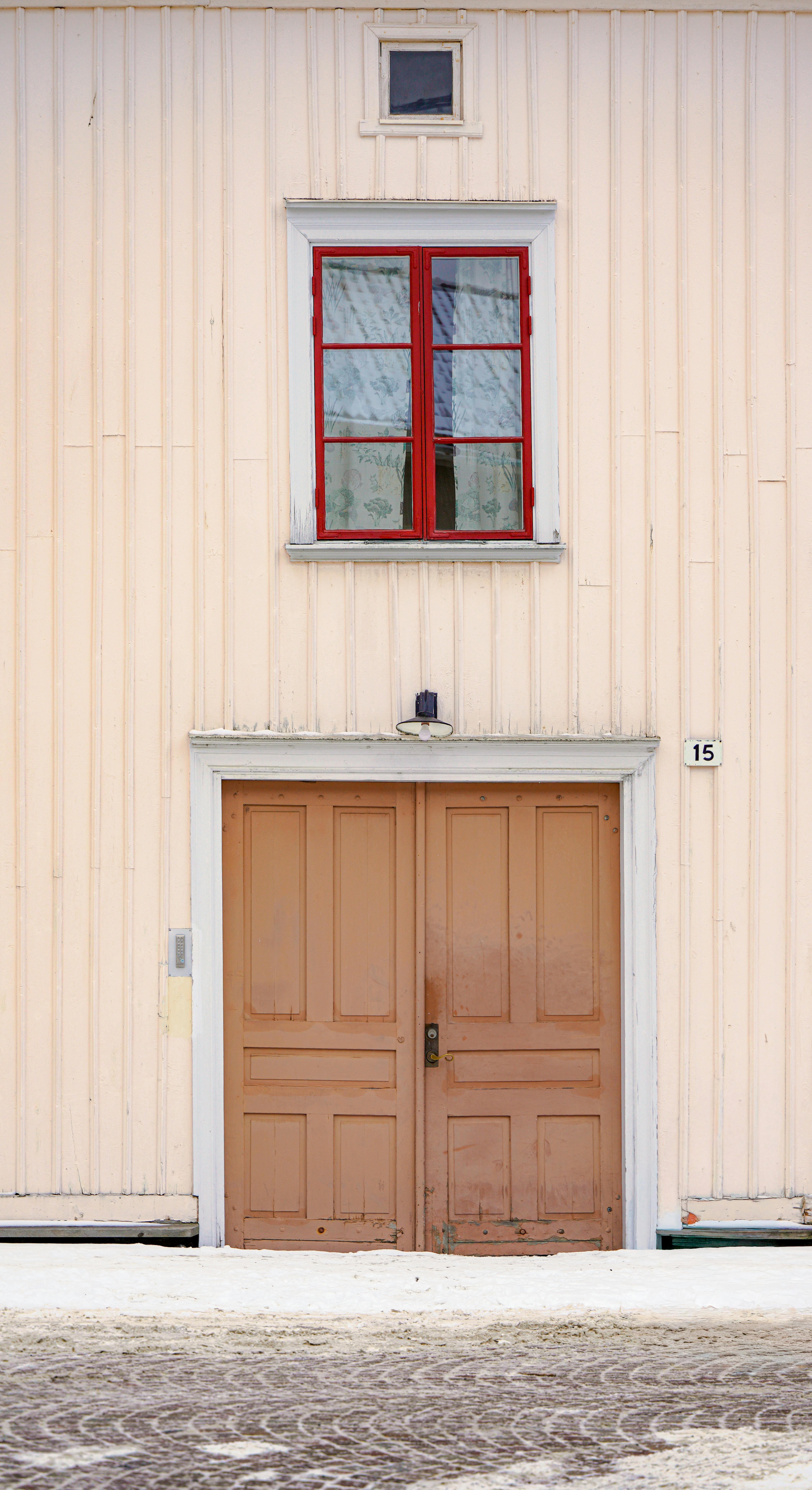 gratis Een charmante gevel van een historisch houten gebouw met een rood omlijst raam en bruine dubbele deuren. Stockfoto