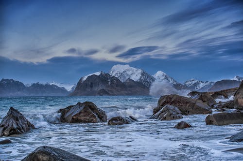 Montañas Rocosas Cubiertas De Nieve Bajo Un Cielo Azul Y Nubes Blancas