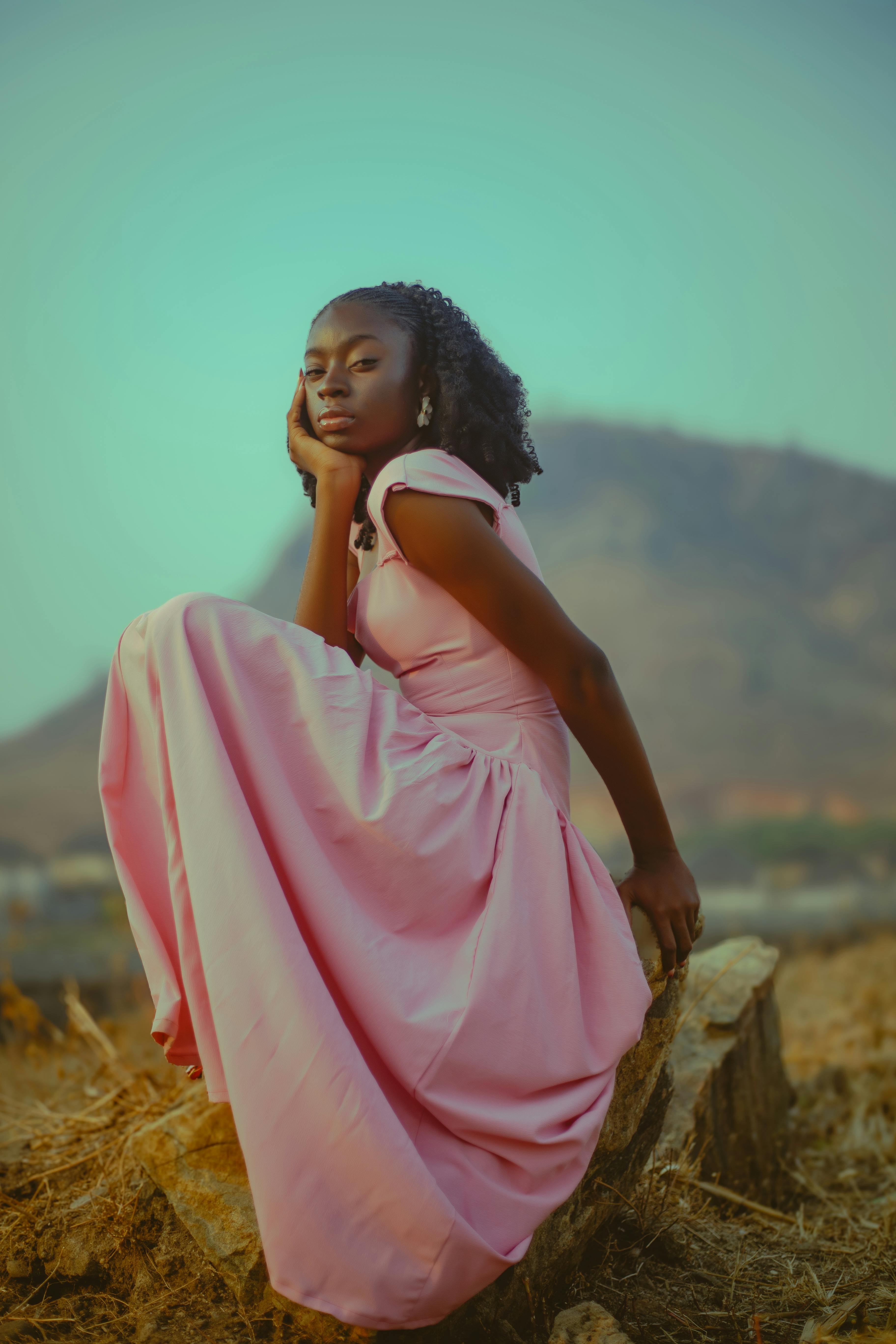 gratis Een jonge vrouw in een roze jurk poseert gracieus tegen een natuurlijke achtergrond, wat elegantie en sereniteit uitstraalt. Stockfoto