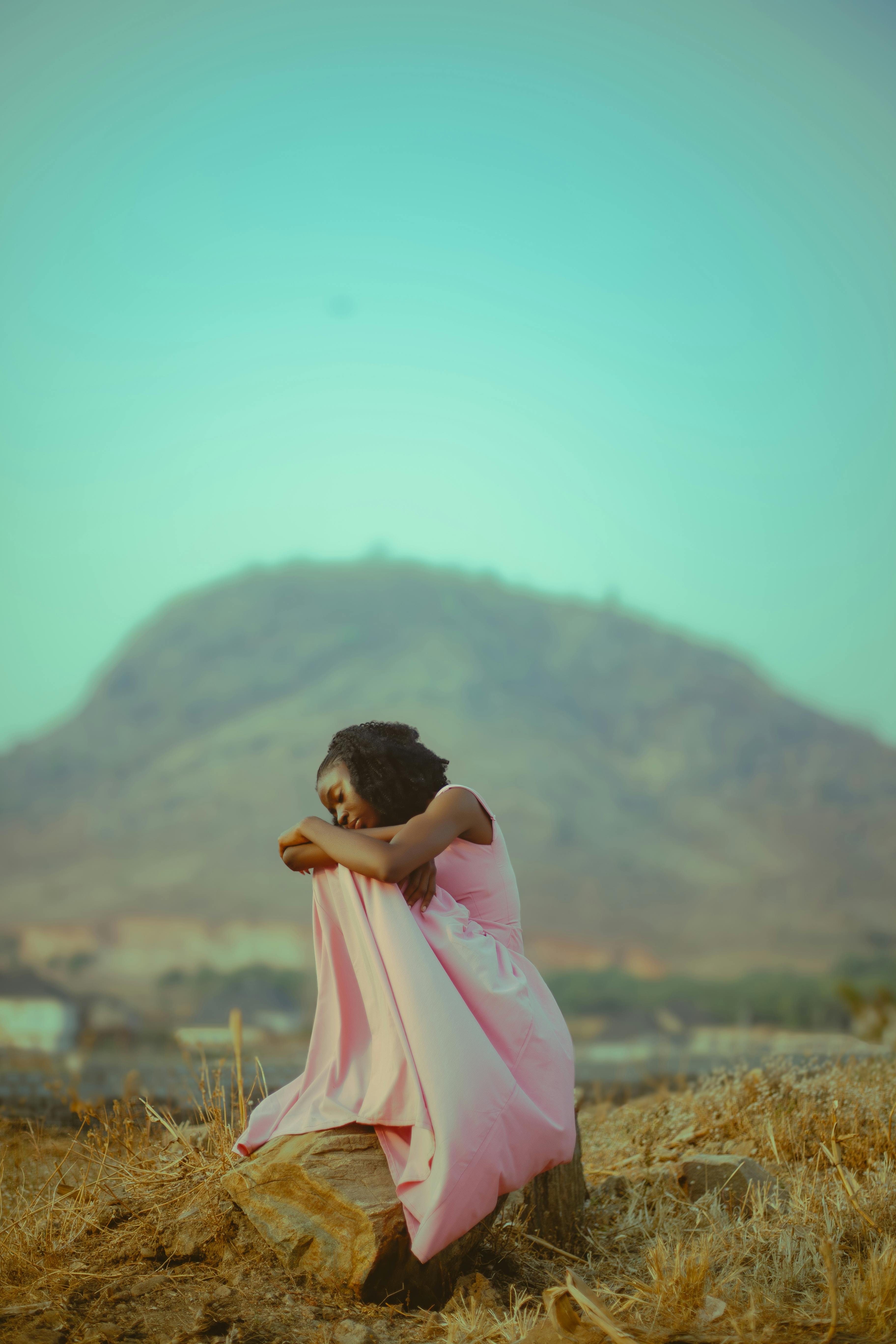 Miễn phí Một người phụ nữ mặc váy hồng ngồi trầm tư giữa khung cảnh núi non thanh bình, ghi lại khoảnh khắc tĩnh lặng. Ảnh lưu trữ