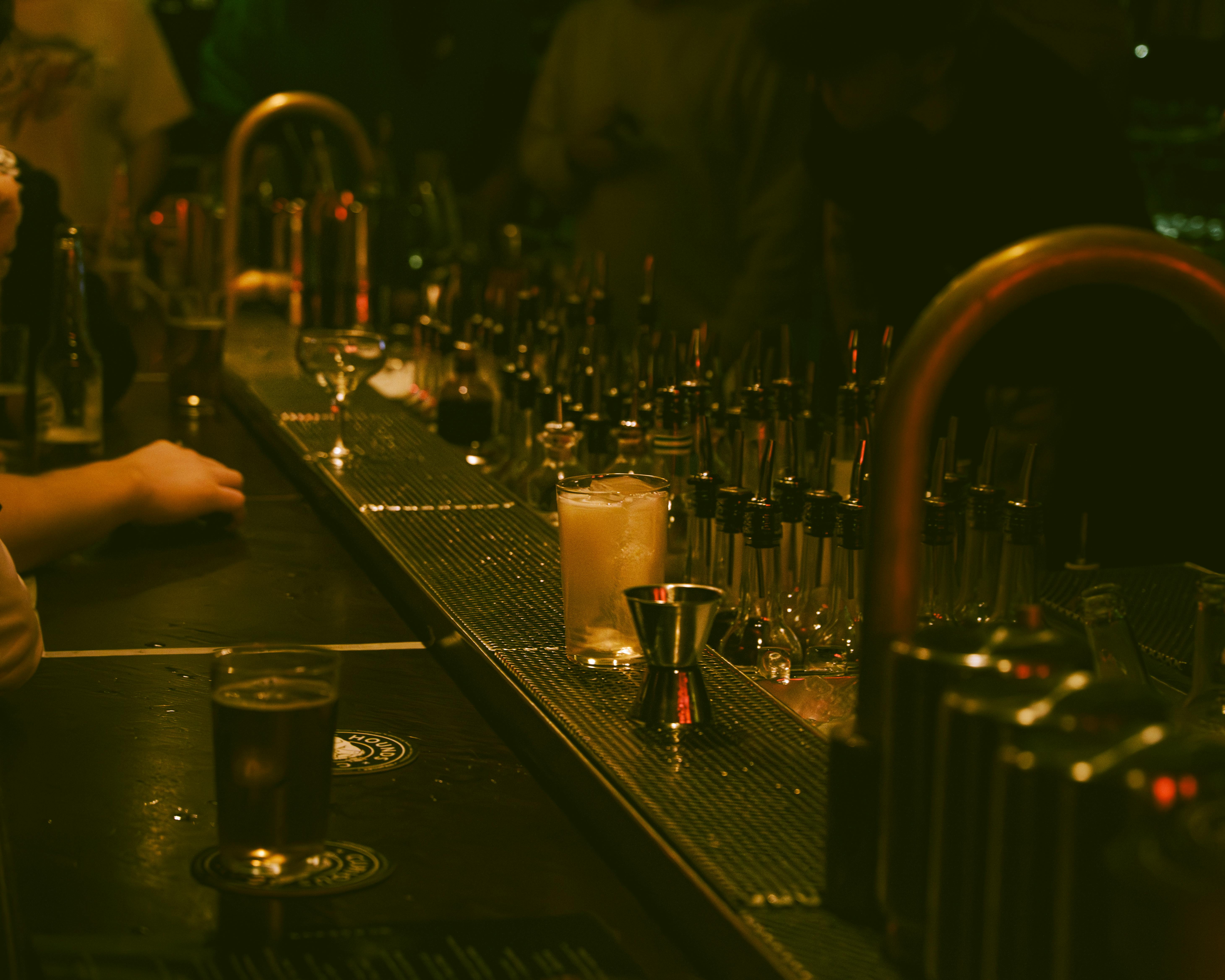 gratis Een schemerig verlichte bar met een drankje en barbenodigdheden die een sfeervolle ambiance creëren. Stockfoto