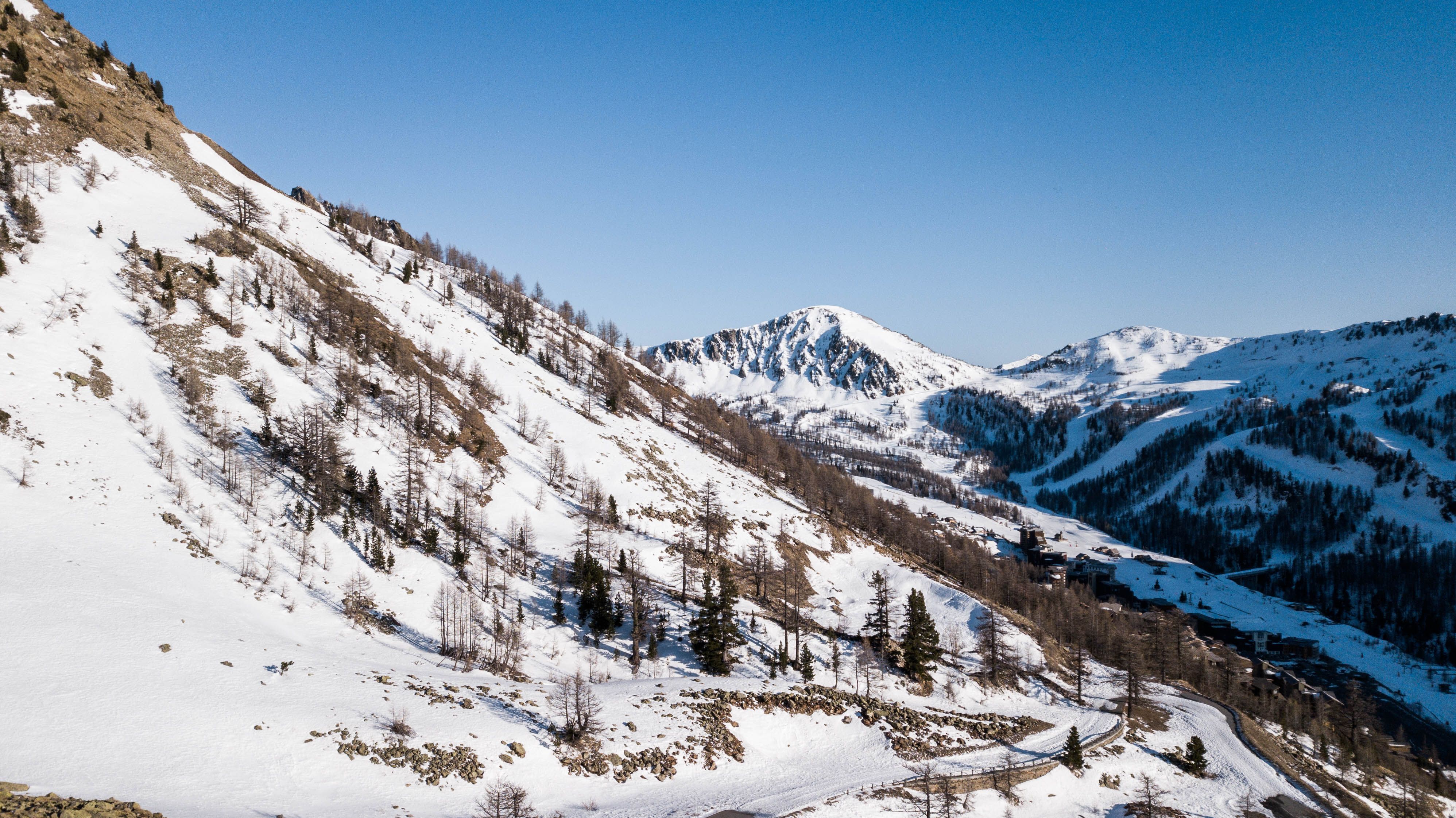 Stunning aerial view of the snow-covered French Alps under a clear blue sky.