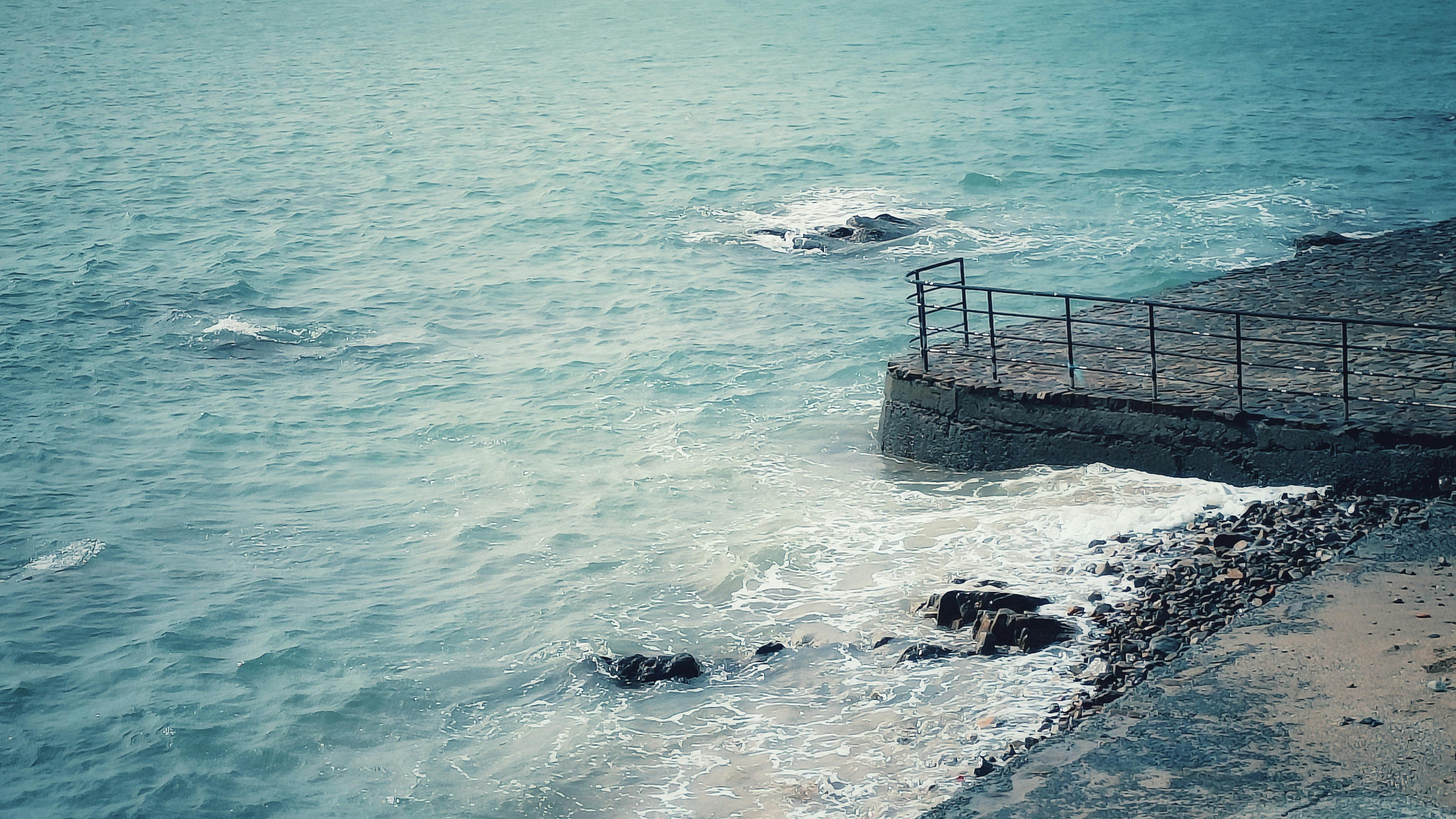 gratis Een vredig kustlandschap met een rotsachtige pier en een turquoise zee, perfect voor thema's als reizen en natuur. Stockfoto