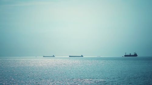 Free Tranquil scene of cargo ships sailing on a shimmering blue ocean under clear skies. Stock Photo
