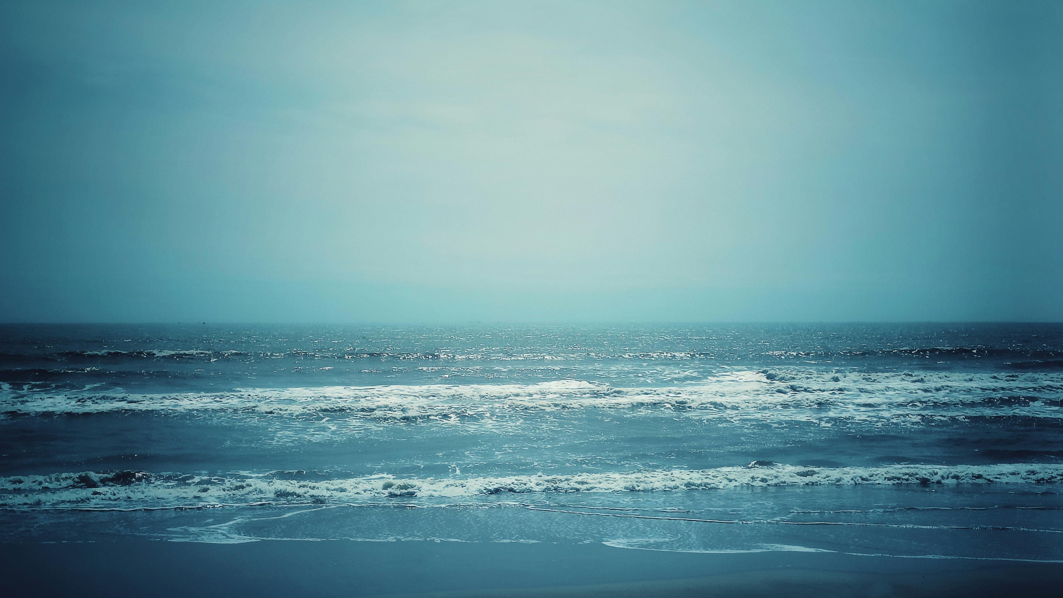 gratis Rustgevend uitzicht op de oceaan met kalmerende blauwe tinten en zachte golven, perfect voor ontspanningsthema's. Stockfoto