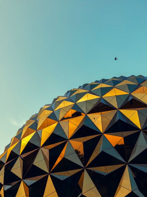 Free Stunning view of a geodesic dome reflecting golden sunrise rays with a bird in sky. Stock Photo