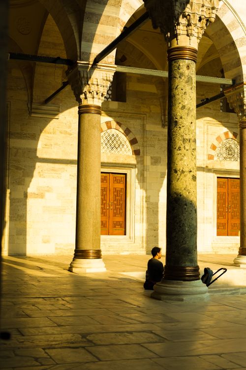 Free A peaceful moment of reflection in a sunlit mosque courtyard, capturing the architectural beauty. Stock Photo