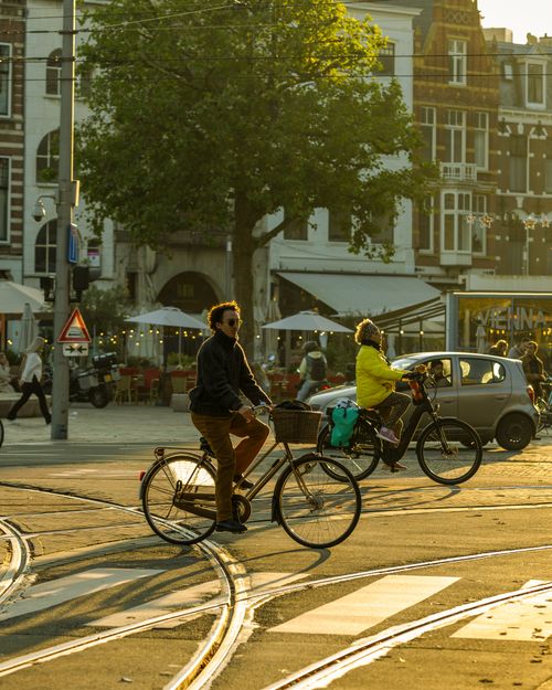 Free Cyclists riding bikes in a sunny street of The Hague, Netherlands, at sunset. Stock Photo