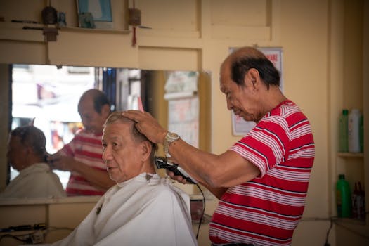 A senior man enjoys a haircut in a classic barbershop setting with a skilled barber.