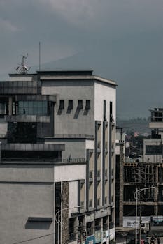 City buildings with a distant mountain view under a cloudy sky.