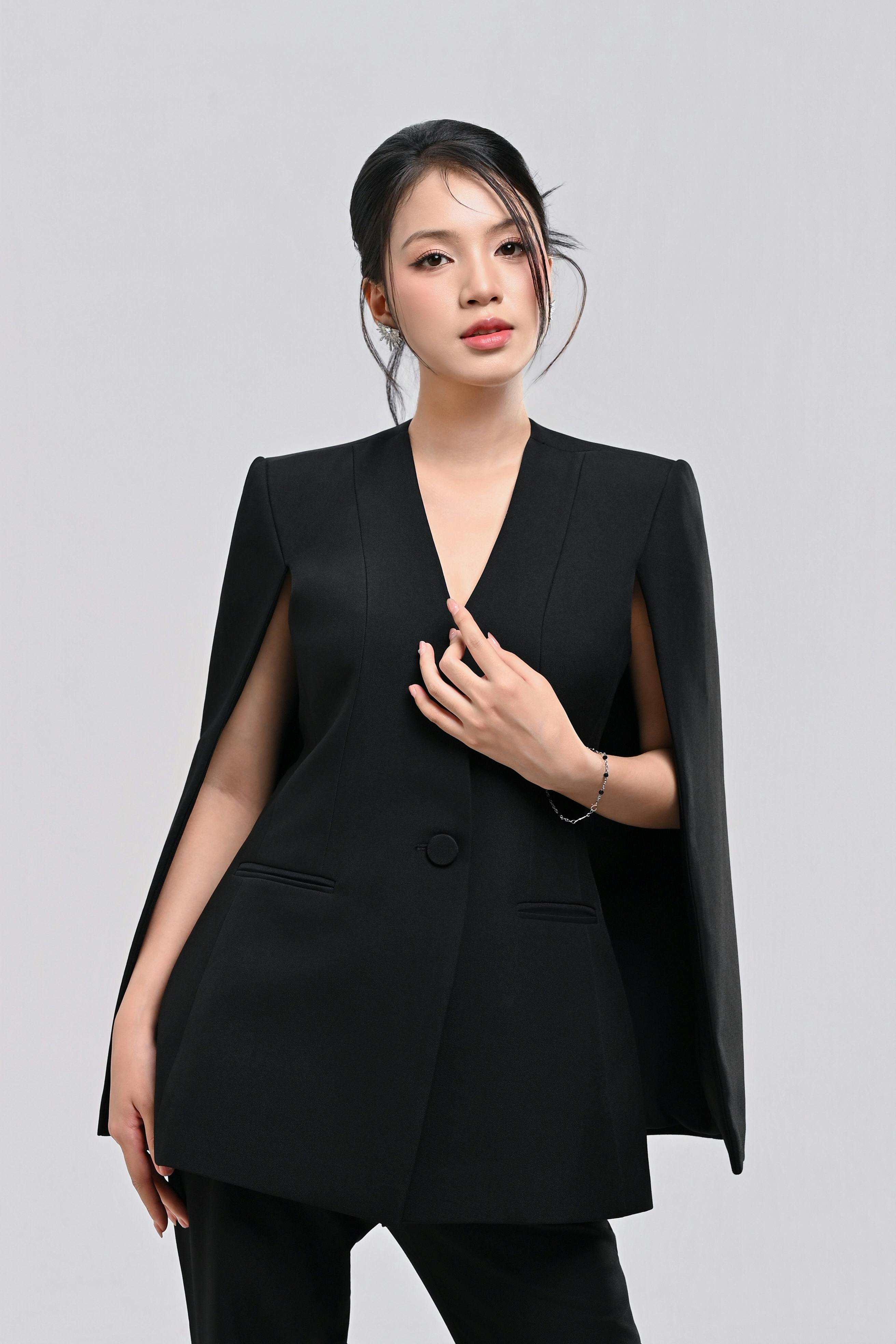 Gratis Donna elegante con un blazer nero a mantella, che mette in mostra moda e stile. Foto a disposizione