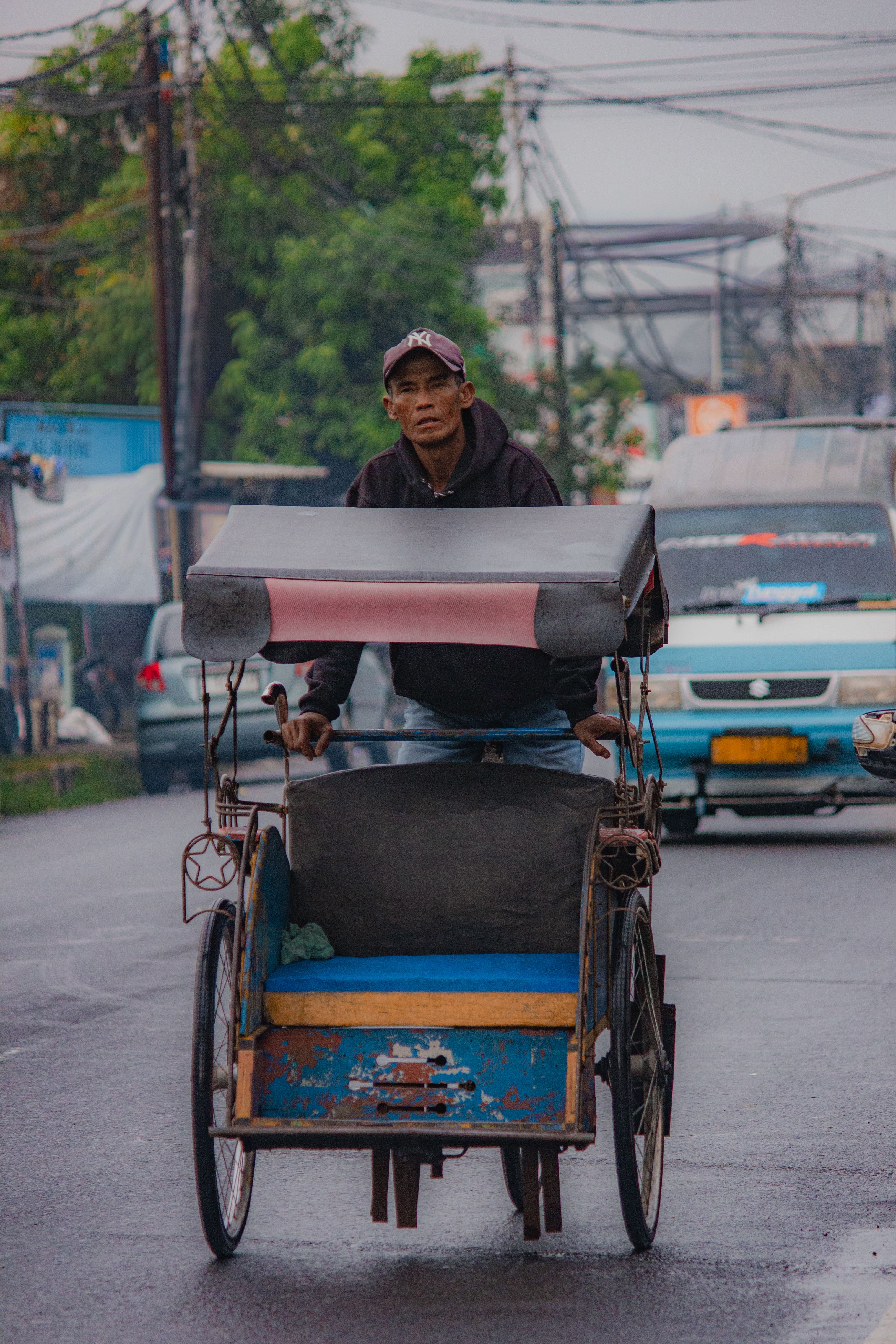 Man Riding Traditional Rickshaw on Urban Street · Free Stock Photo