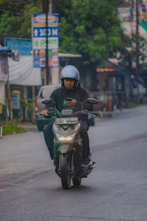 Free A person riding a scooter in an urban area while looking at a phone. Stock Photo