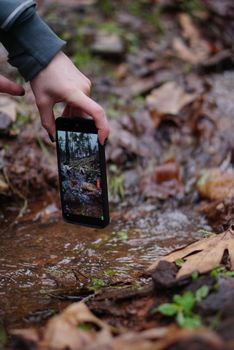 A hand holding a phone capturing a stream in Kahramanmaraş, Turkey.