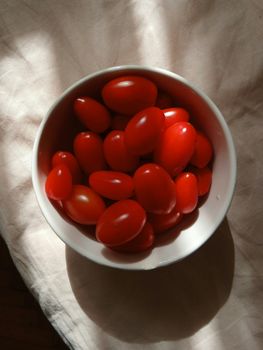 A bowl of vibrant, fresh cherry tomatoes placed in natural light.