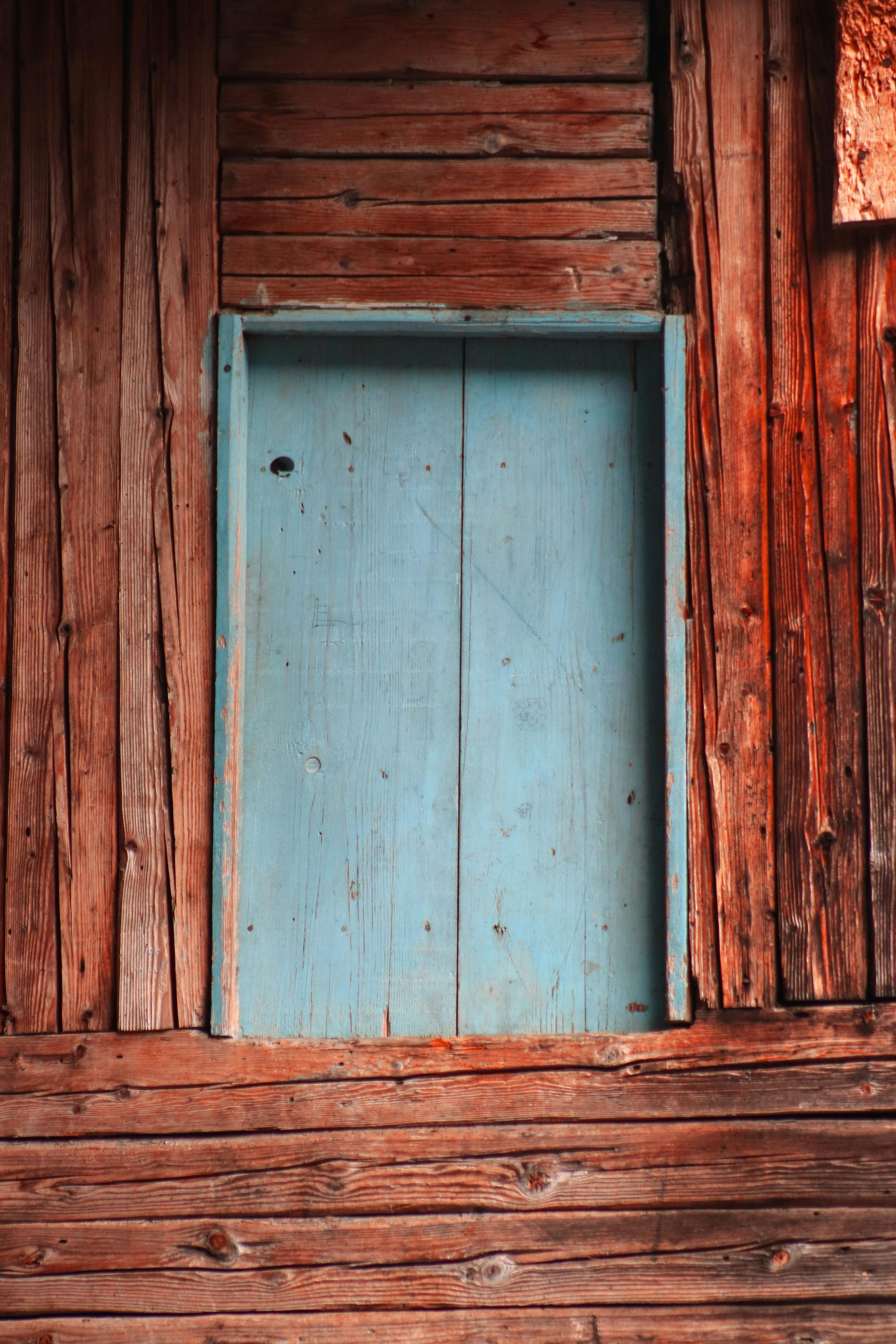 Gratuit Un perete simplu, rustic, din lemn, cu o ușă albastră vintage, decorată în tonuri calde și naturale. Fotografie de stoc
