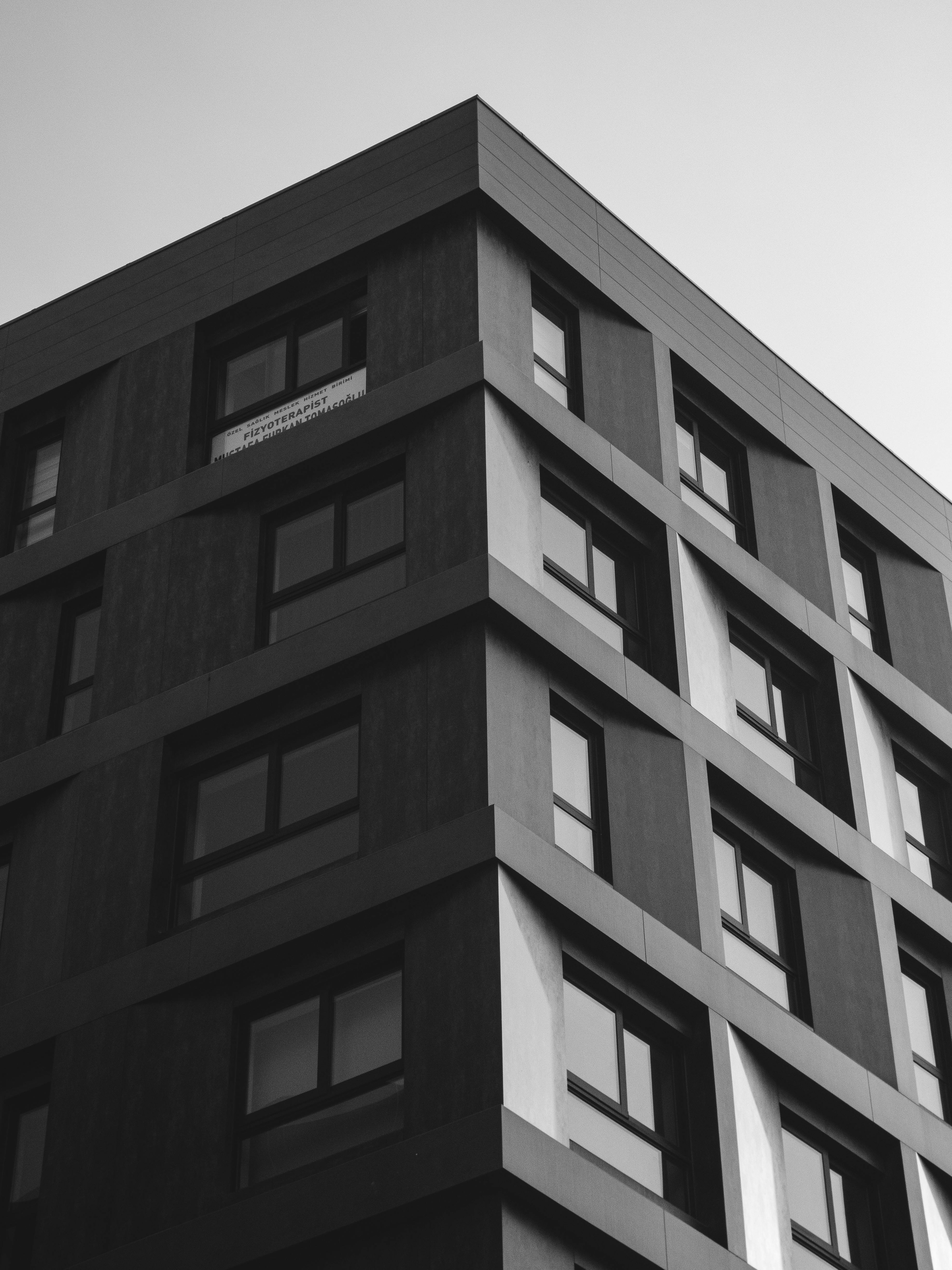 Kostnadsfria En modern flervåningsbyggnad fångad i ett svartvitt fotografi, som visar upp dess moderna arkitektur. Stock foto