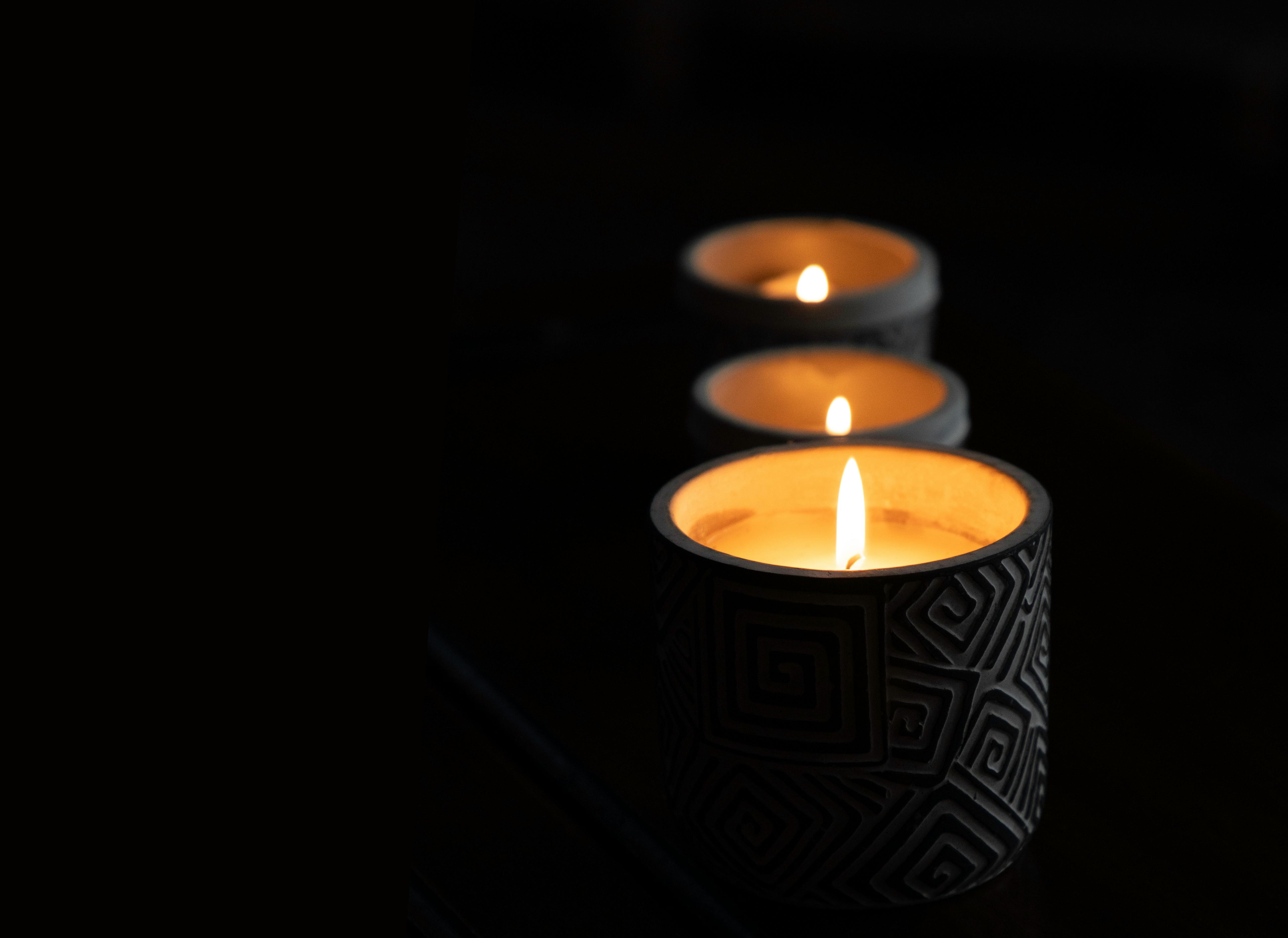 gratis Drie brandende kaarsen in decoratieve houders verspreiden een warme gloed en creëren een serene sfeer. Stockfoto